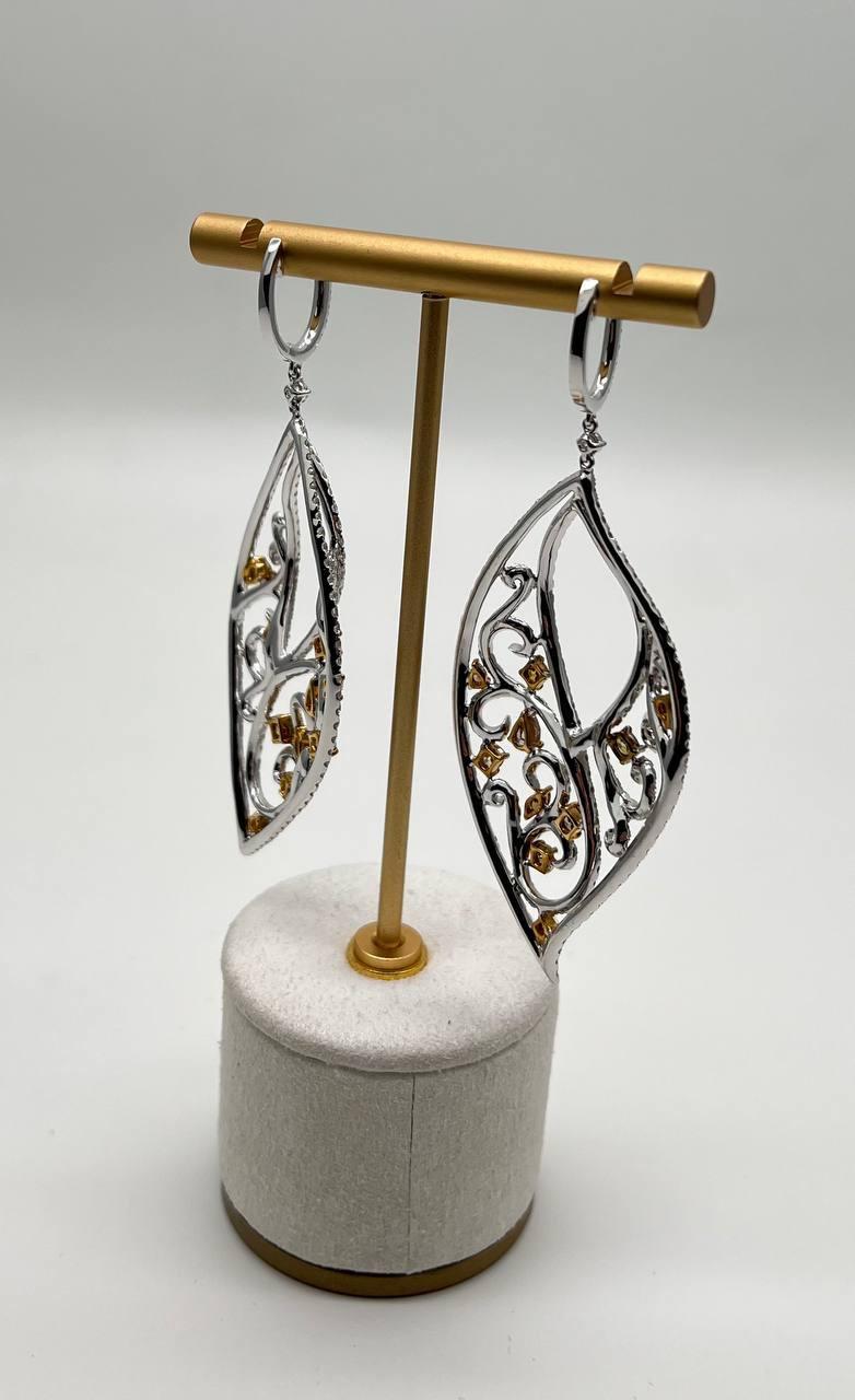 Entdecken Sie die Eleganz dieser exquisiten Ohrringe.

Sie sind mit einem filigranen Gitter aus funkelnden Diamanten versehen, die in 18 Karat Weißgold gefasst sind.

Die Ohrringe sind mit einer harmonischen Mischung aus weißen und bernsteinfarbenen