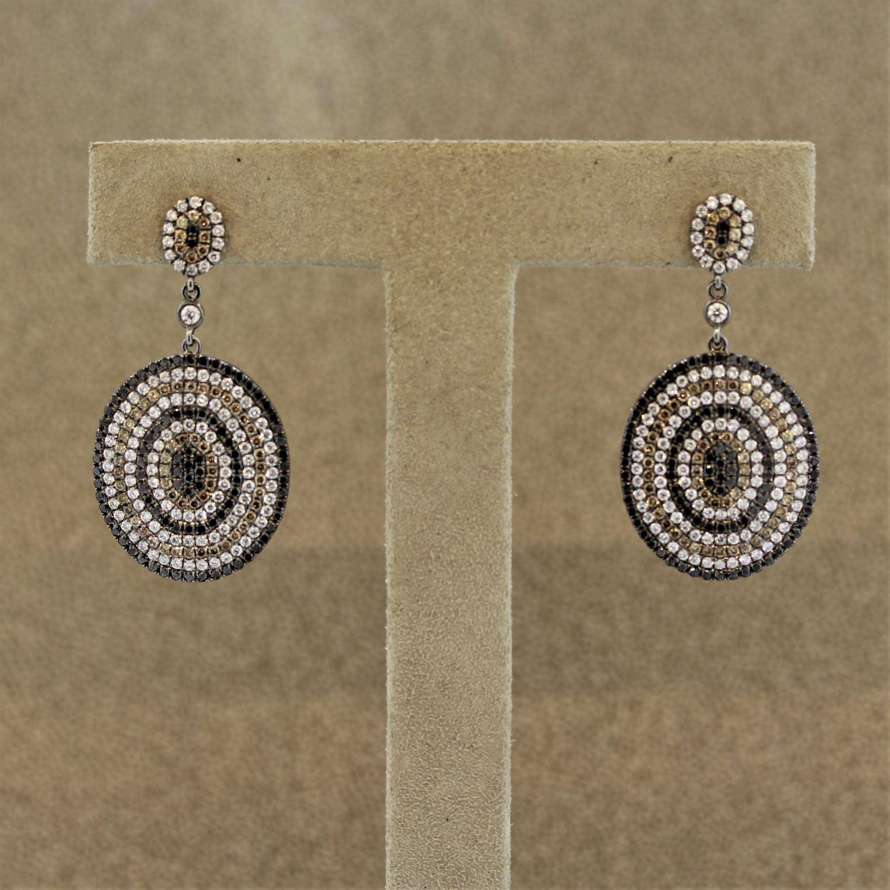 A unique pair of earrings made in 18k gold with a black rhodium finish giving the gold a darker metallic look. They feature fancy black and cognac colored diamonds along with classic colorless white diamonds which are set in a pattern. They weigh a