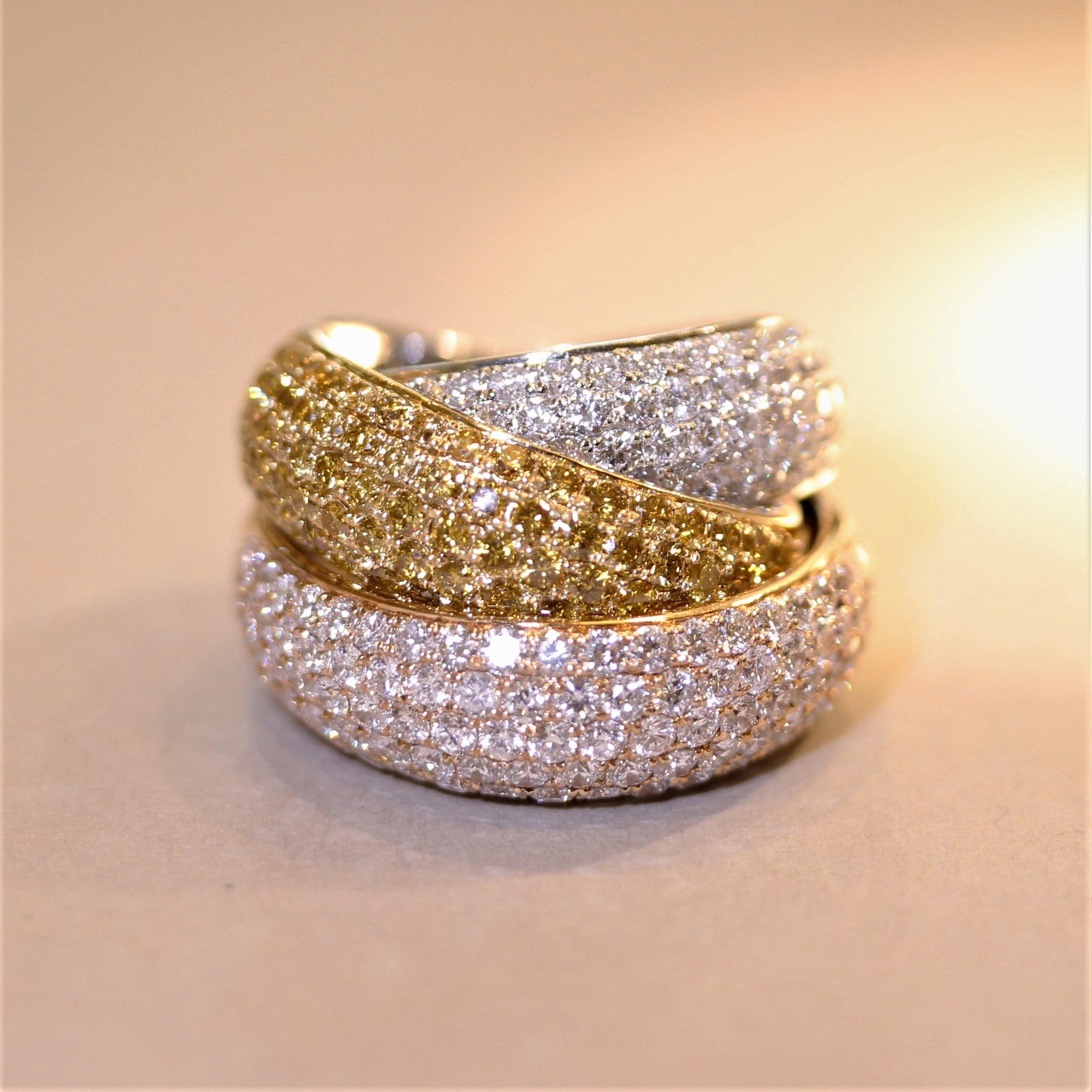 A stunning piece of high jewelry! This tri-colored gold crossover ring features fancy-yellow, colorless and fancy light pink diamonds! They are all fine quality and cut as round brilliants, weighing a total of 6.50 carats. The yellow diamonds are