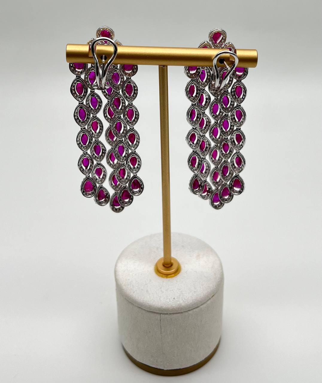 Ein auffälliges Paar Ohrringe, jedes mit einer aufwendigen Verzierung aus 18-karätigem Weißgold versehen, mit einer Kaskade aus leuchtend roten, rosafarbenen Rubinen. Das Design zeigt eine Reihe von marquiseförmigen Fassungen, die jeweils einen