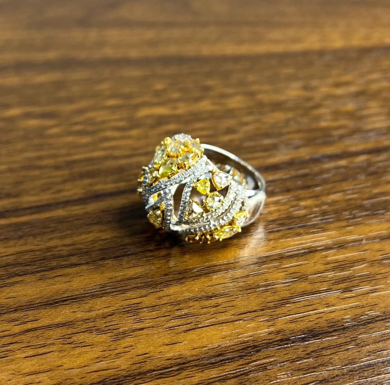 Ein auffälliger und kunstvoller Ring mit einem verschlungenen Muster aus leuchtend gelben Saphiren und weißen Diamanten.

Der Ring ist mit einer Mischung aus birnen- und rundförmigen Edelsteinen verziert, die in einem wirbelnden Muster gefasst sind,