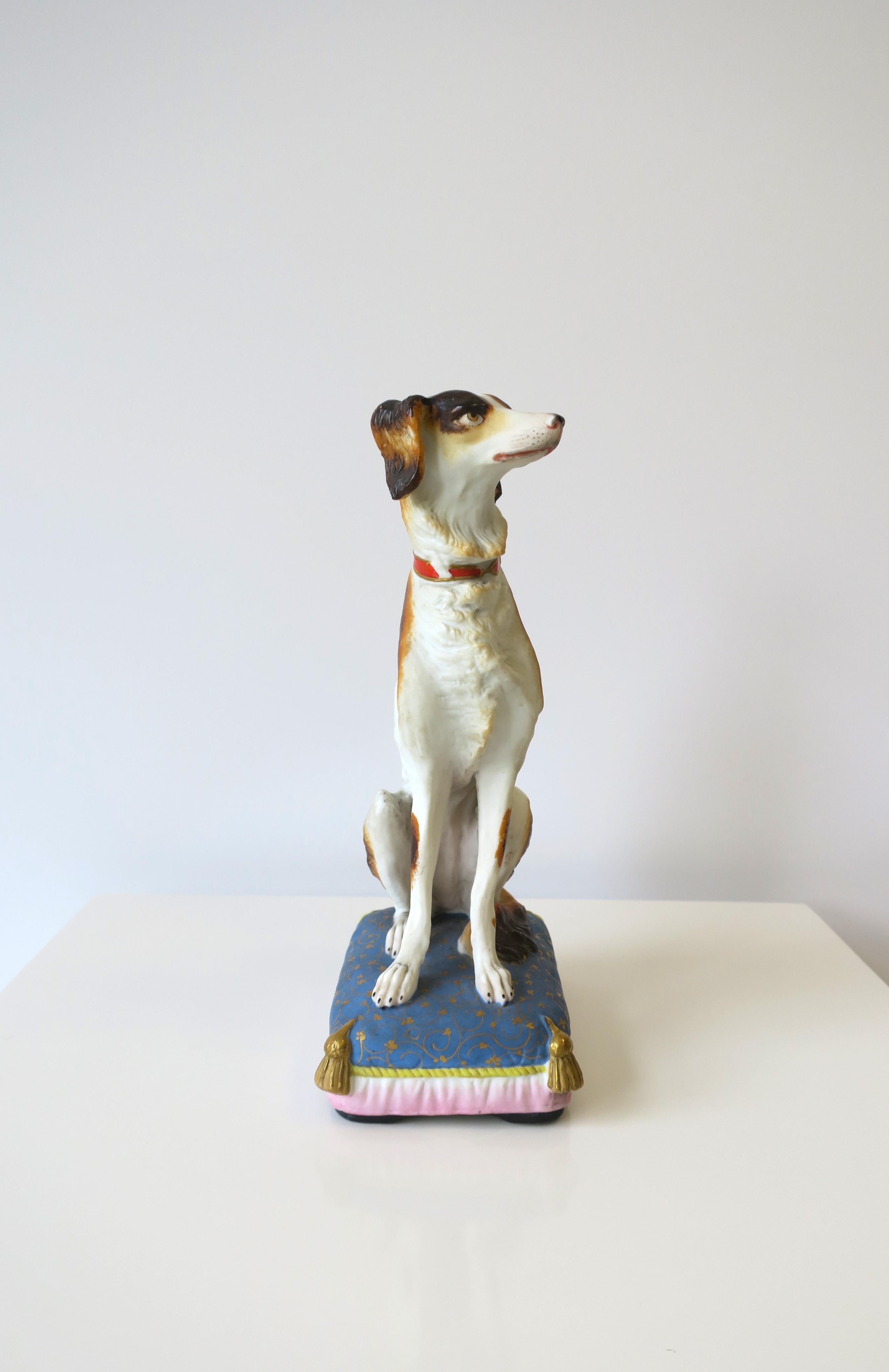 A beautiful porcelain regal dog sitting on fancy pillow, circa mid-20th century. A great decorative object. Piece is matte unglazed porcelain ceramic of a brown and white dog, a red and gold collar, sitting on fluffy blue pillow with yellow and gold