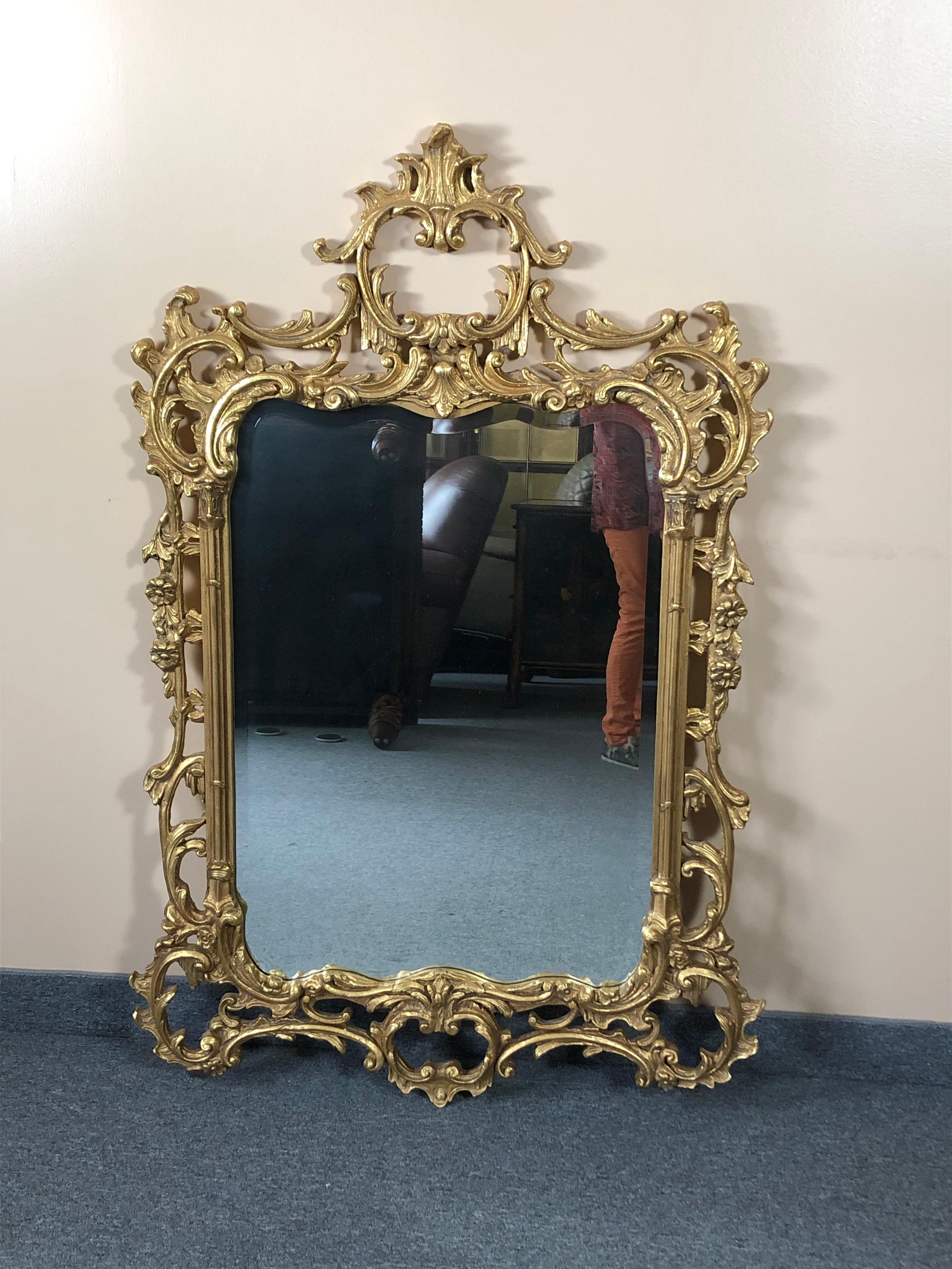 Dramatic giltwood rococo style mirror with curlicues and gesso embellishments. Mirror is bevelled and top quality.