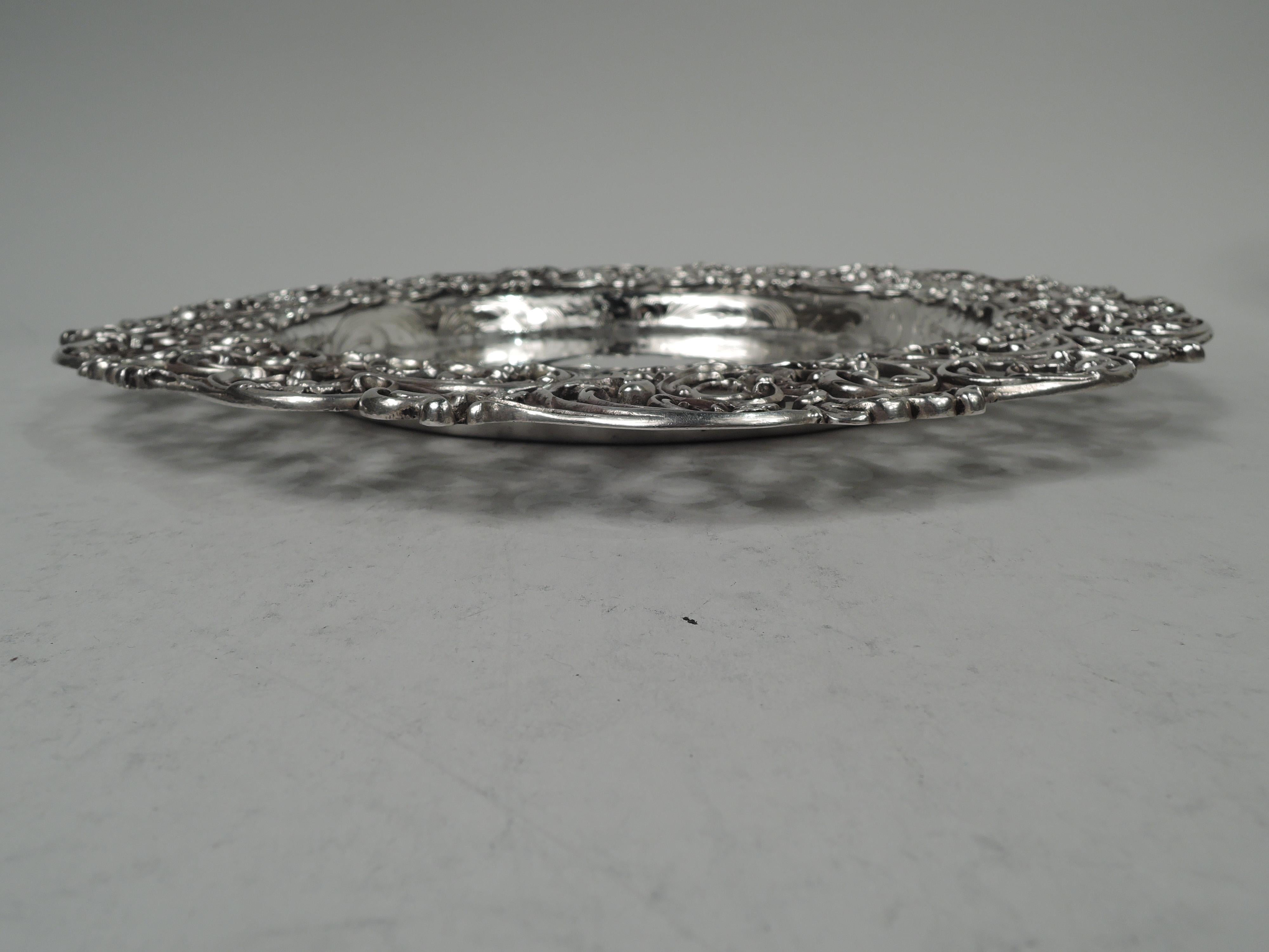 Fancy Victorian sterling silver cake plate. Made by Gorham in Providence, ca 1890. Round and deep well engraved with leafing scrolls and flowers; center vacant. Applied and cast wide and open rim with same. Fully marked including maker’s stamp and