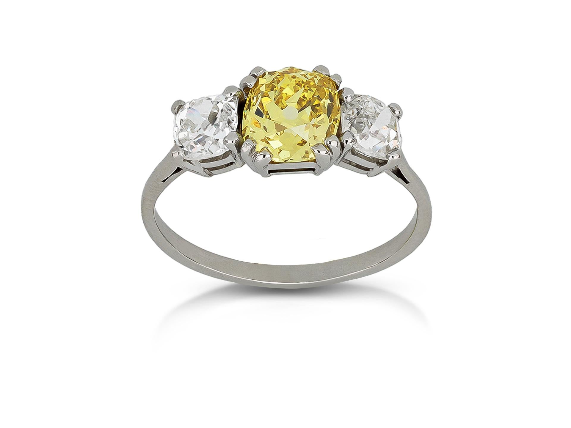 Anello a tre pietre con diamante giallo intenso. Al centro è incastonato un diamante giallo intenso naturale fancy a forma di cuscino, di purezza VS2, con un peso di 1,46 carati in un'incastonatura a griffe aperta sul retro, affiancato da due
