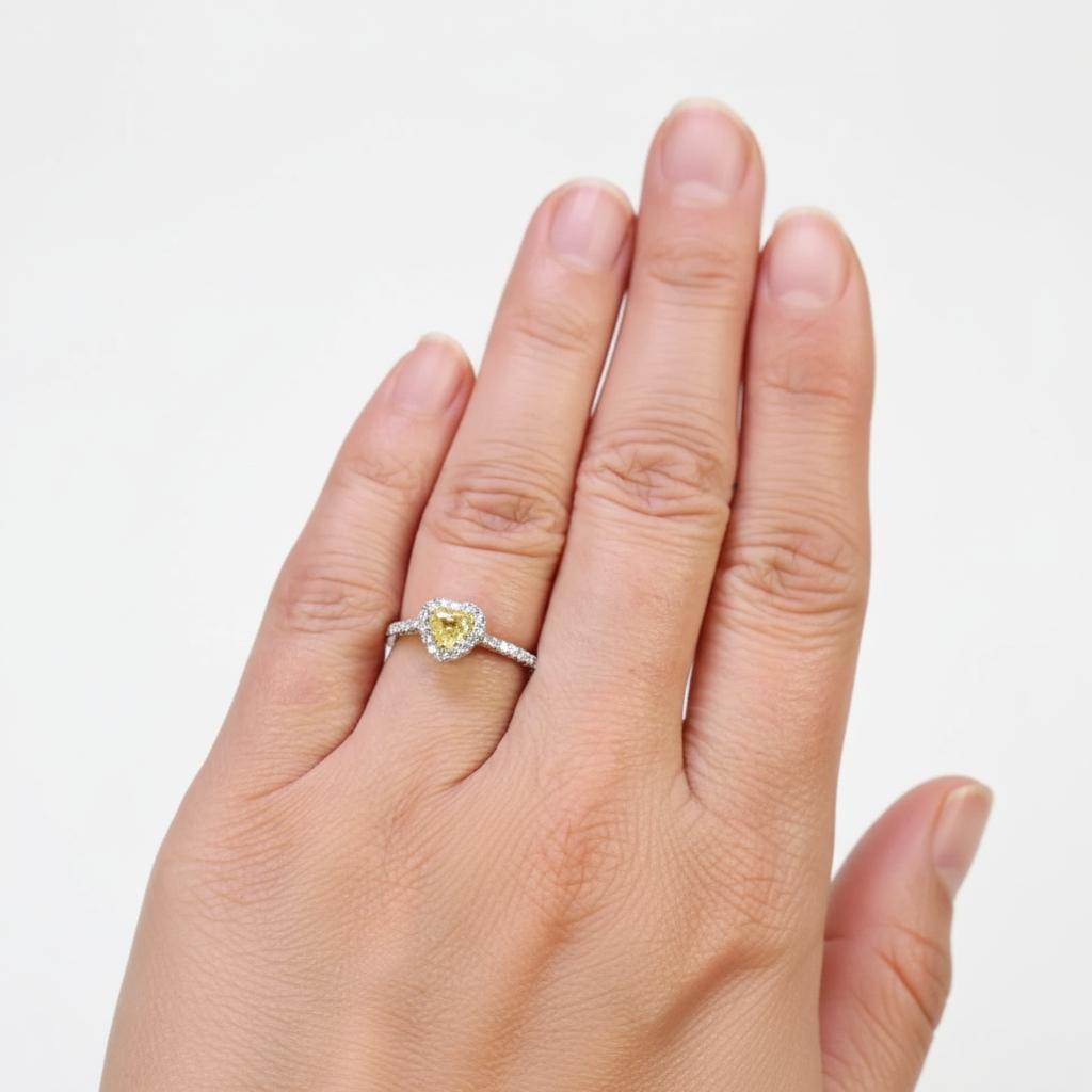 Radieuse et romantique, cette bague exquise est ornée d'un éblouissant diamant en forme de cœur de 0,38 carat de couleur Fancy Intense Yellow - une teinte vibrante et pure sans aucune nuance brune. La saturation et la brillance du diamant sont
