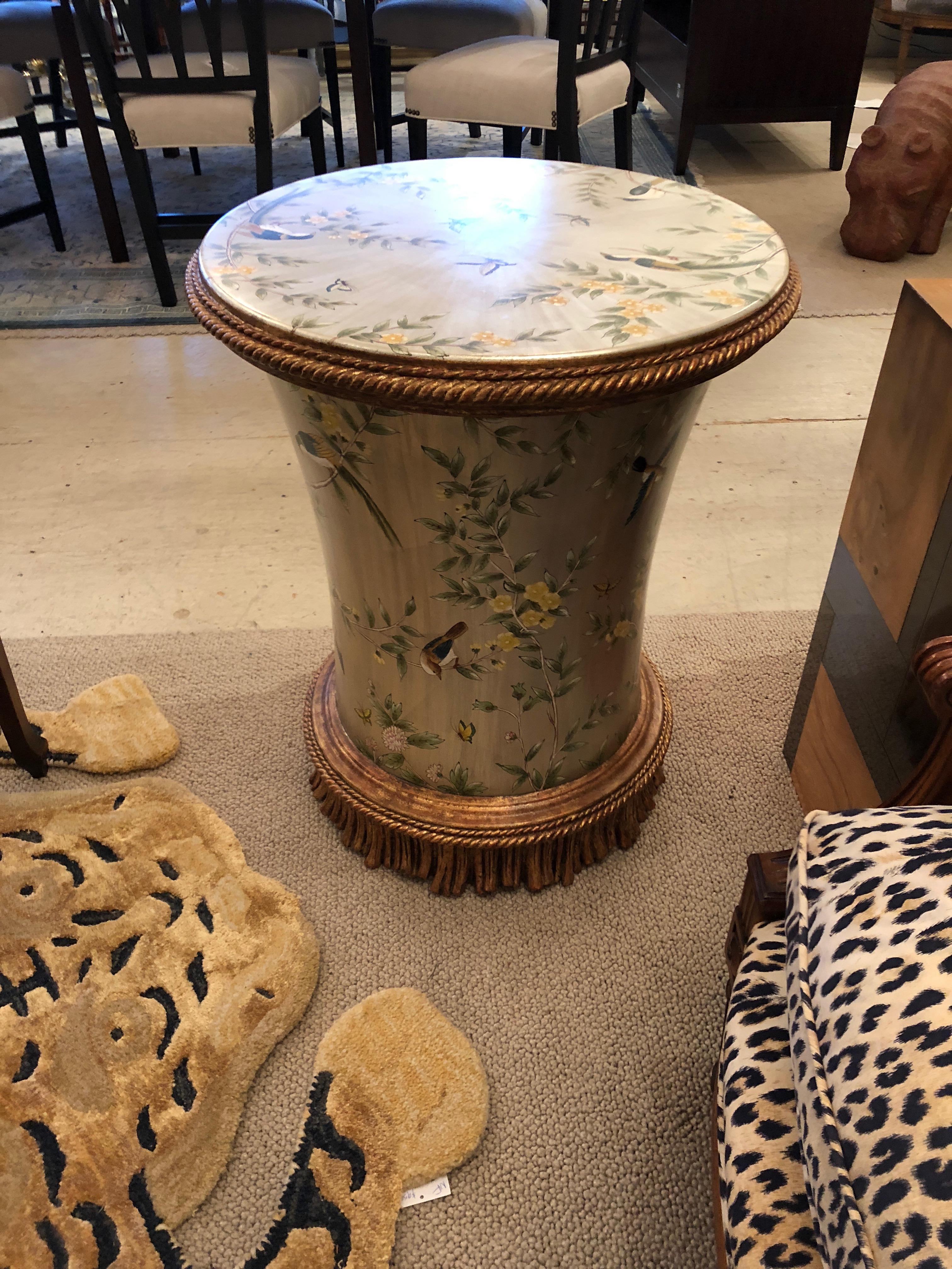 Glamorous circular side or end table having silver leaf background and wonderful motife of birds, flowers and butterflies, reminiscent of Gracie wallpaper. Fabulous bronze gold colored decorative carved wood fringe on the bottom and border around