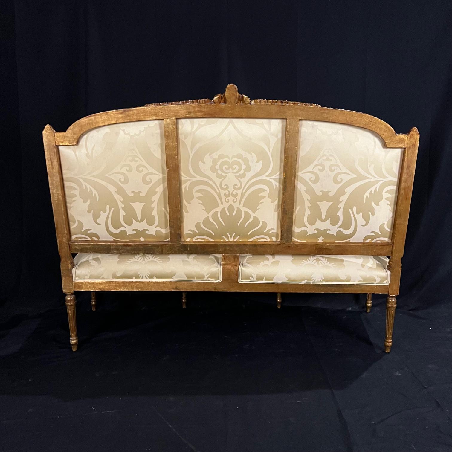 Louis XVI style sofa having carved gilded wood and beautiful new upholstery. The lovely frame displays fluted columns topped by acanthus leaves. The base is composed of fluted and tapered feet. The belt and the crosspieces are decorated with water