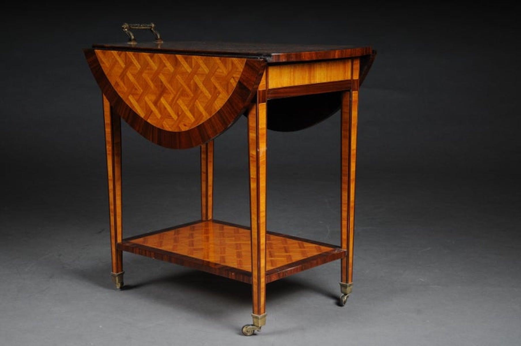 Fancy, noble bar table / serving table / side table.

Solid wood with inlaid veneer. Straight frame base on conical square legs in bronze caps ending with rolls. Deep drawer on the side. Slightly protruding, double sided folding tabletop.
