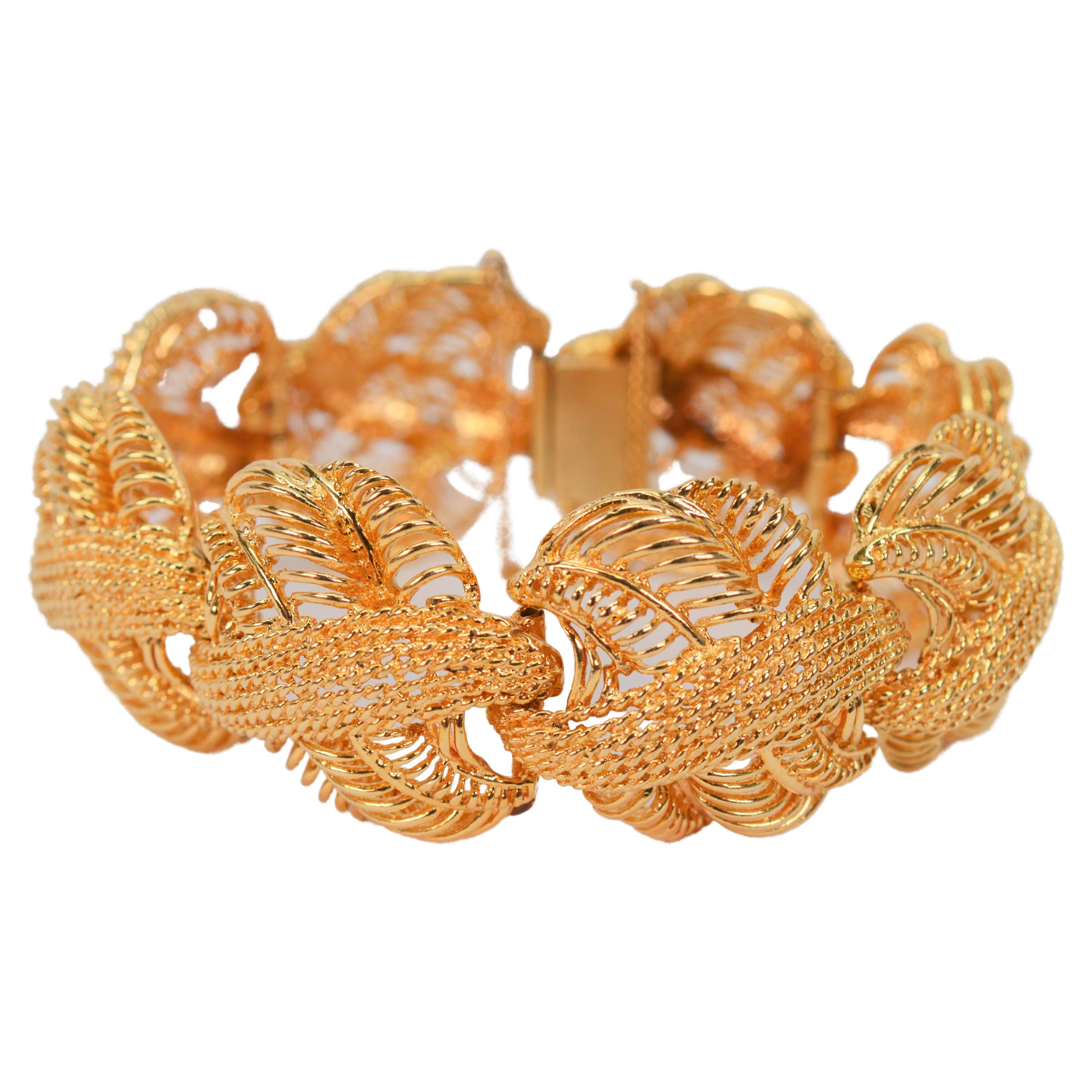 A fancy open weave in bright fourteen karat 14K yellow gold gives this boldly stylish rosette inspired gold bracelet its true elegance. Crafted convex woven gold links, measuring approximately one inch, are each individually hinged and give this