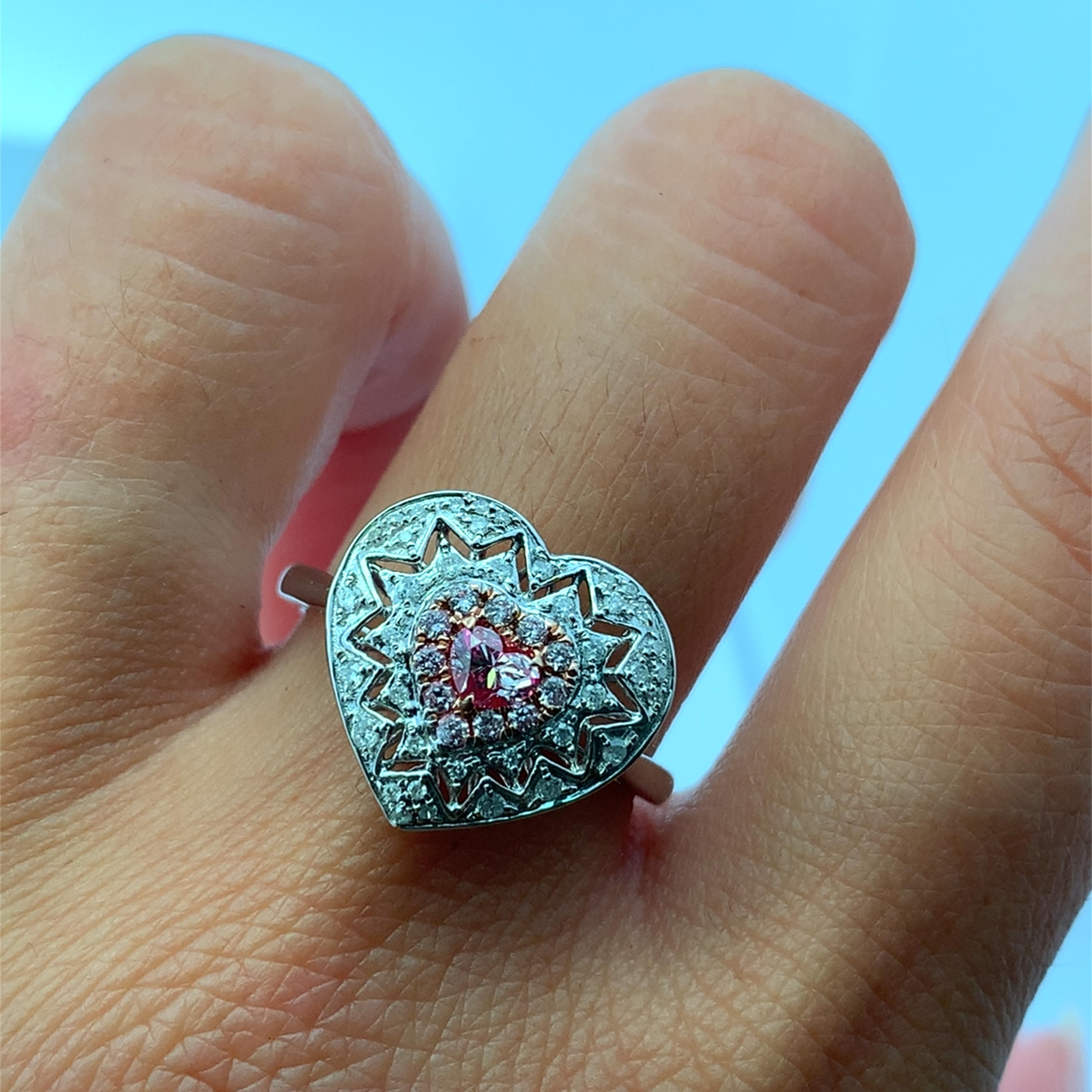 Squisito anello con diamante rosa fantasia a forma di cuore che presenta un diamante rosa fantasia a forma di cuore con un diamante bianco a taglio brillante, incastonato in un anello di fidanzamento in oro bianco 18 carati. Questo anello ha un