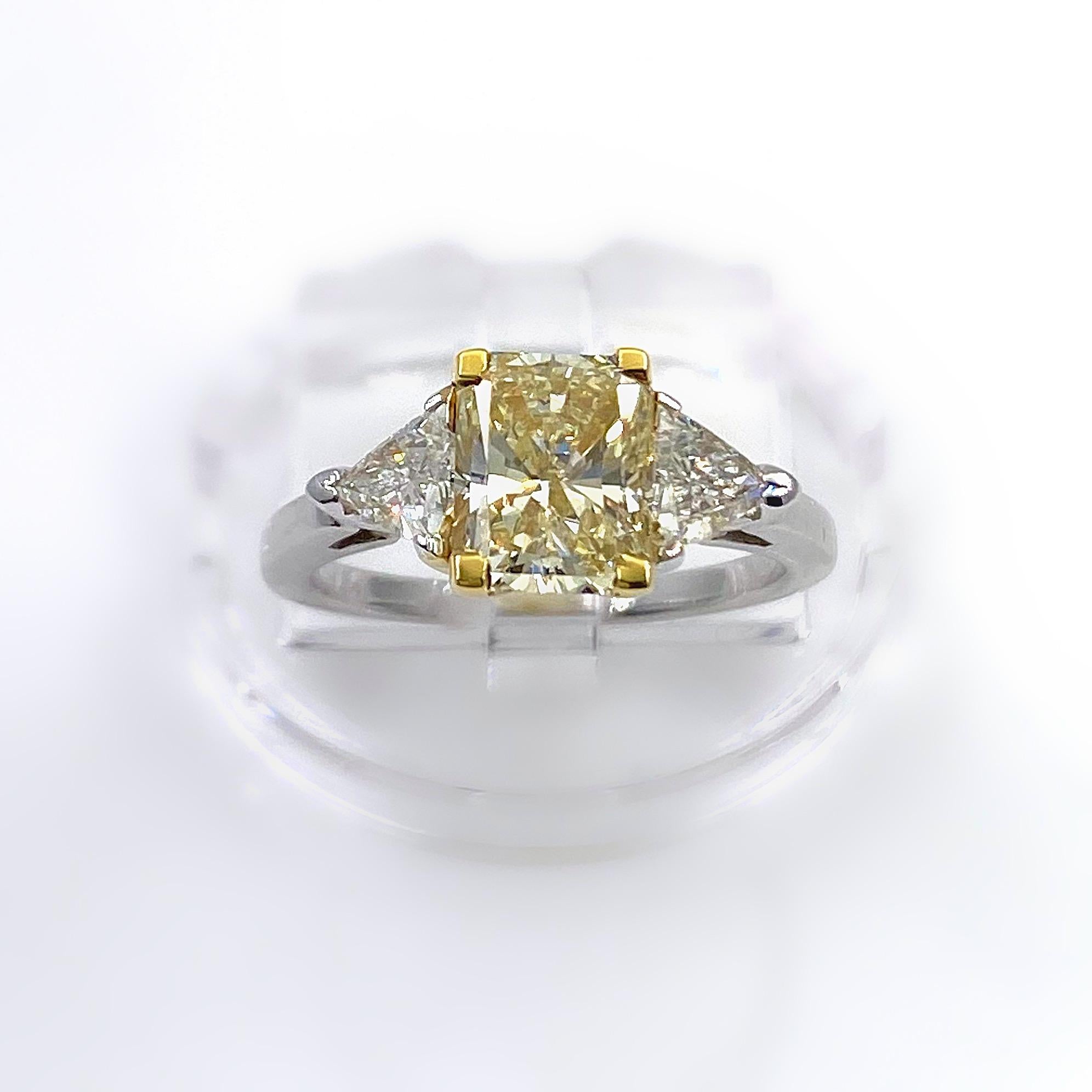 Radiant Diamond Ring
Style:  Fancy Three-Stone Diamond Engagement Ring
Metal:  14K White & Yellow Gold
Size / Measurements:  5, sizable
TCW:  2.11 Carats Total
Main Diamond:  1.61 Carat Radiant Cut Diamond
Color & Clarity:  Fancy Light Yellow,  VS1