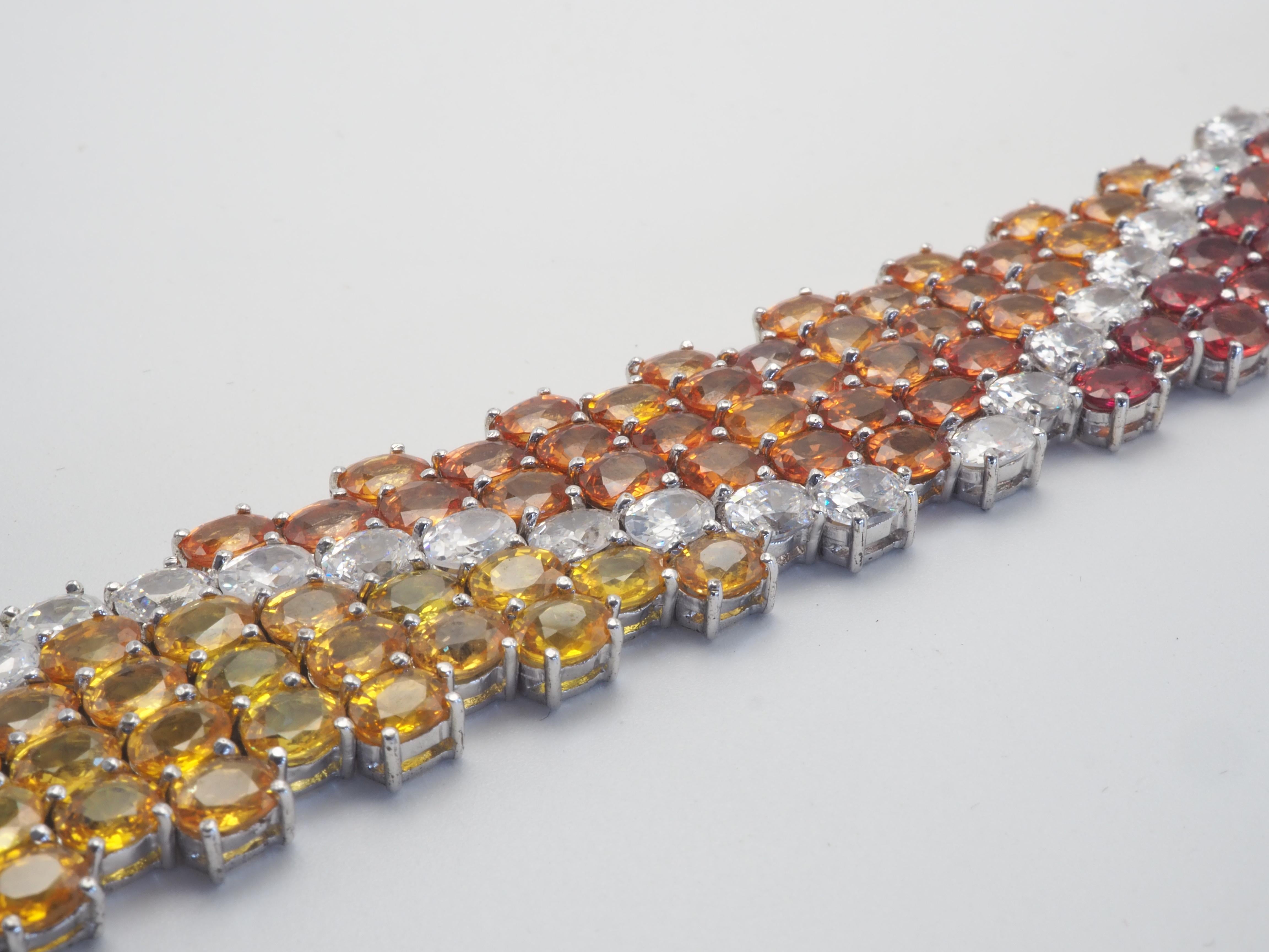 A very beautiful and elegant cocktail bracelet in solid sterling silver with multi color natural oval sapphires- bright and colorful. Rainbow themed bracelet with thickness and splendor. White quartz zigzagged through the sea of colorful sapphires