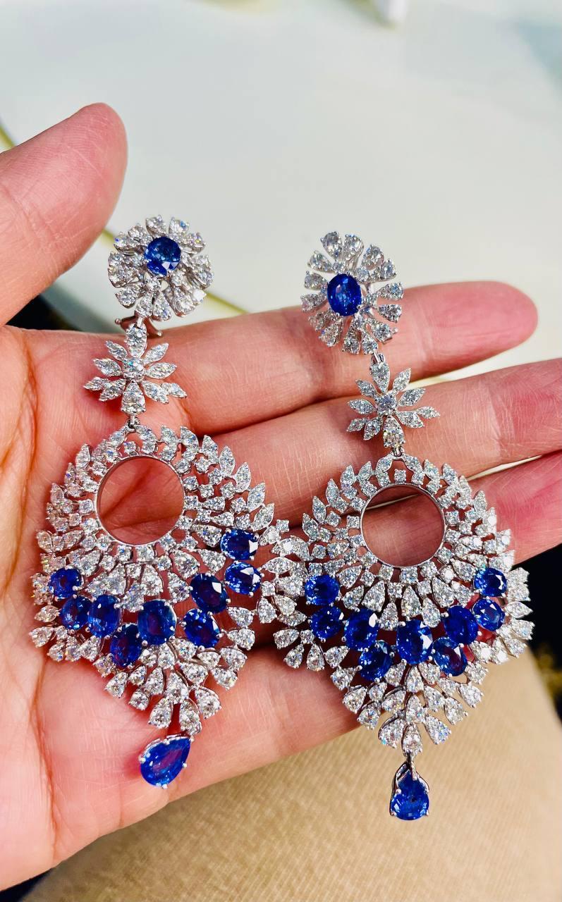 Discover the elegance of these exquisite earrings:

Featuring a stunning array of deep blue sapphires, these earrings are intricately designed with a circular motif adorned with sparkling diamonds.

The top showcases a floral diamond pattern