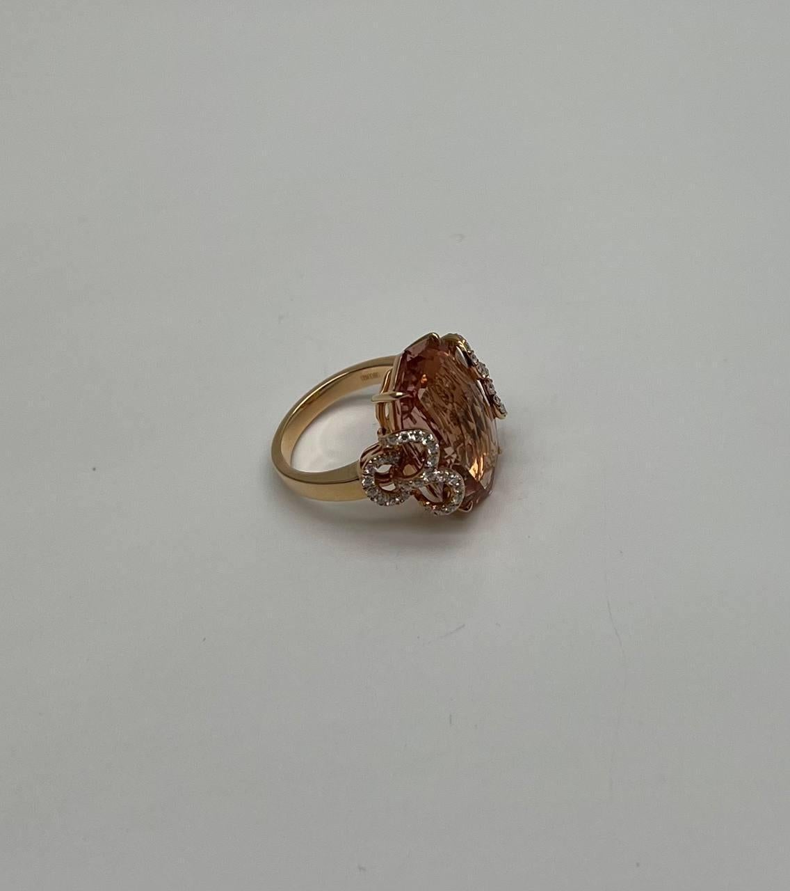 Un anello sorprendente ed elegante con una grande morganite rosa sfaccettata color pesca.
L'anello è impreziosito da intricati accenti di diamanti che esaltano la pietra centrale con un tocco di brillantezza.
Questo pezzo squisito è stato progettato