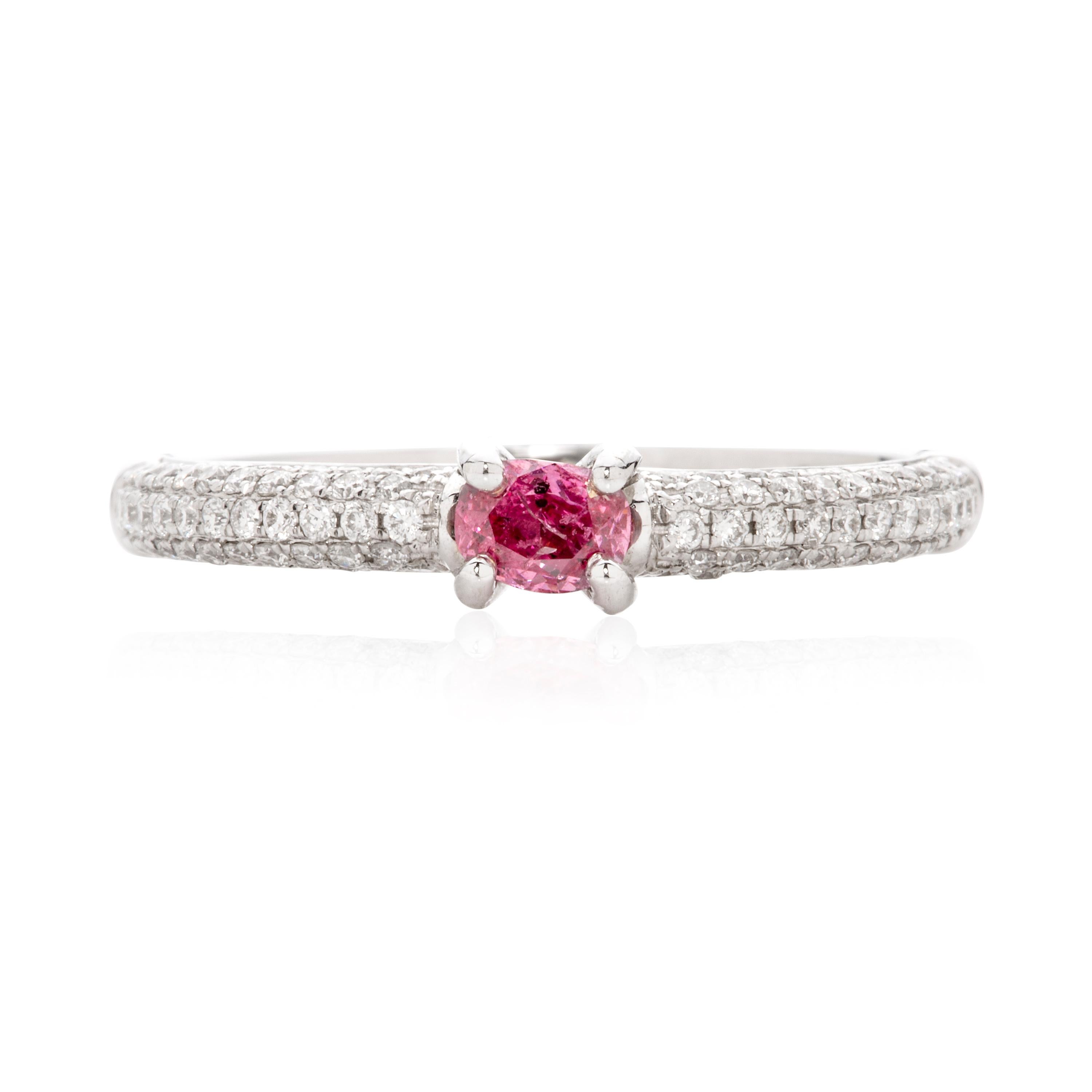 An 18 karat white gold ring featuring a GIA certified 0.18 carat fancy vivid purplish pink diamond (clarity: I2). The shoulders of the ring are set with 78 round brilliant cut white diamonds (clarity: VS-SI) totalling 0.29 carats. The ring size is N