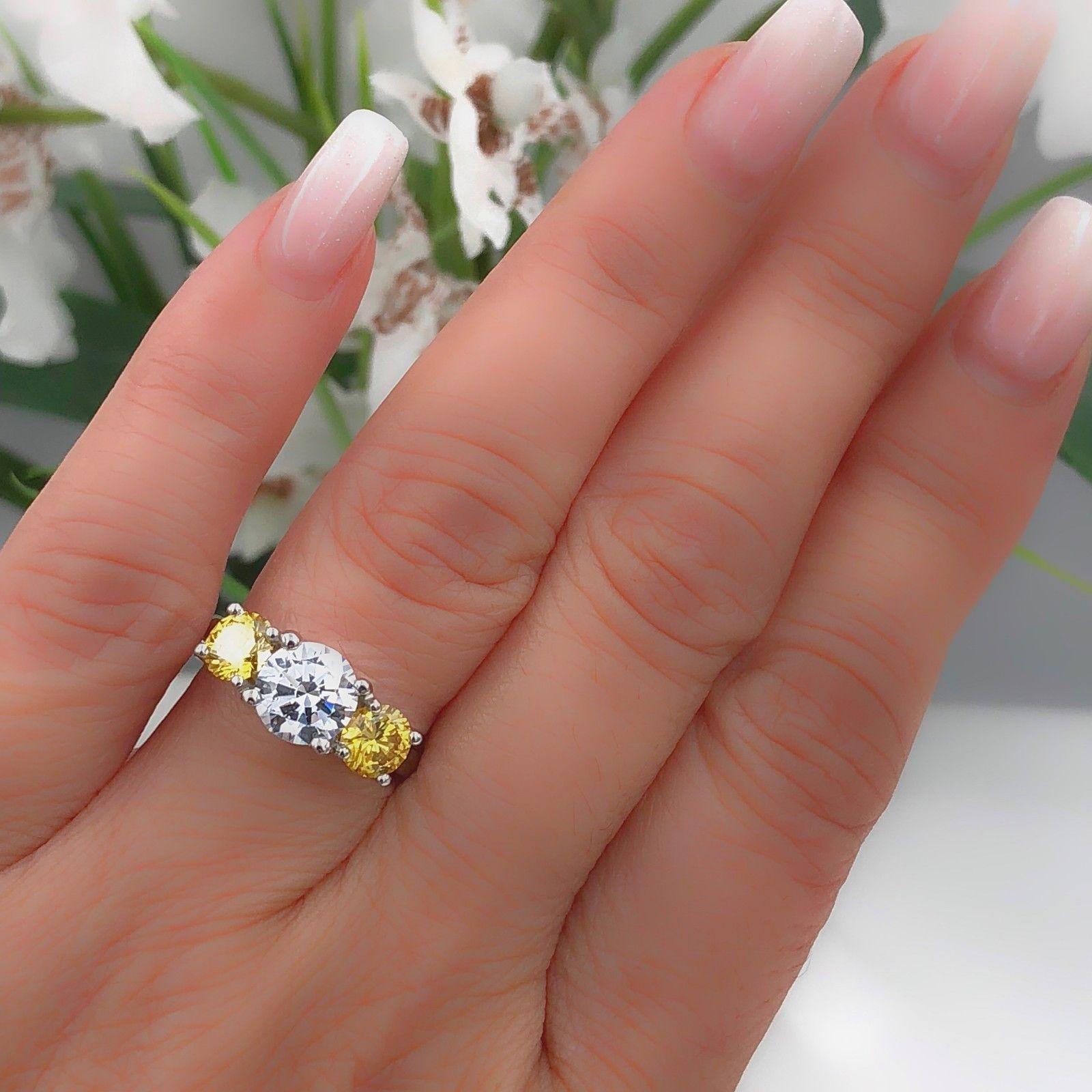Style:  Three-Stone Fancy Yellow Diamonds Semi-Mount for Round Brilliant Center
Serial Number:  GIA #16417149 / GIA #16417152
Metal: Platinum
Size:  5.5 - sizable
Center will hold a Round Brilliant Diamond ~1.00-2.00 cts 
Side Stones #1:  Round