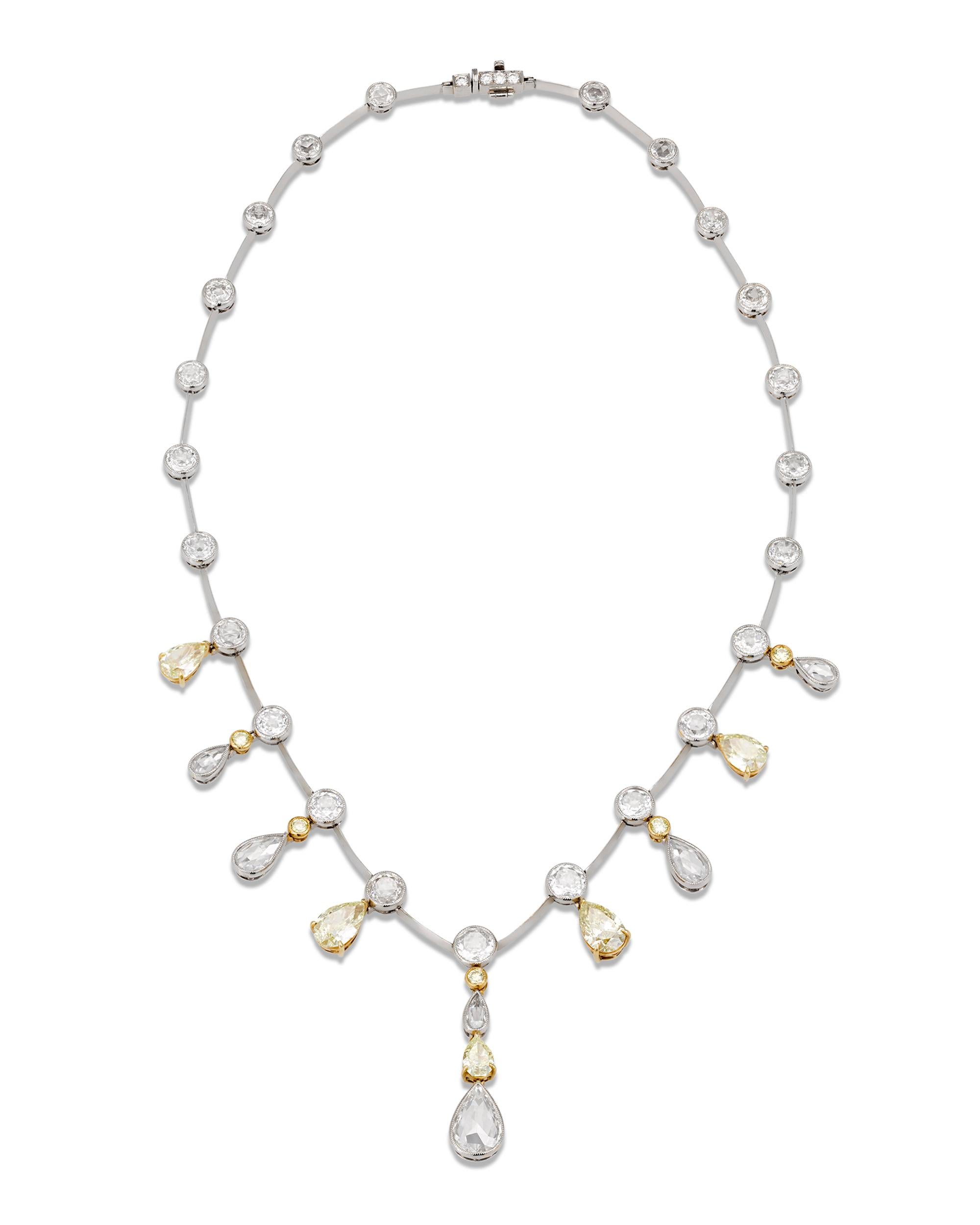 This sensational necklace showcases an exquisite design illuminated by extraordinary stones. Eleven dramatic pear-shaped fancy yellow and white diamonds dangle from bezel-set round brilliant-cut diamonds, gracefully falling around the neck. The
