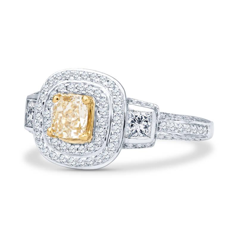 This one of a kind engagement ring is set in an 18kt white gold band and features a 0.45ctw fancy yellow cushion cut diamond center stone of VS1-VS2 quality. It is bordered by two .40ctw princess cut diamonds of F/G color and VS2-SI1 quality.