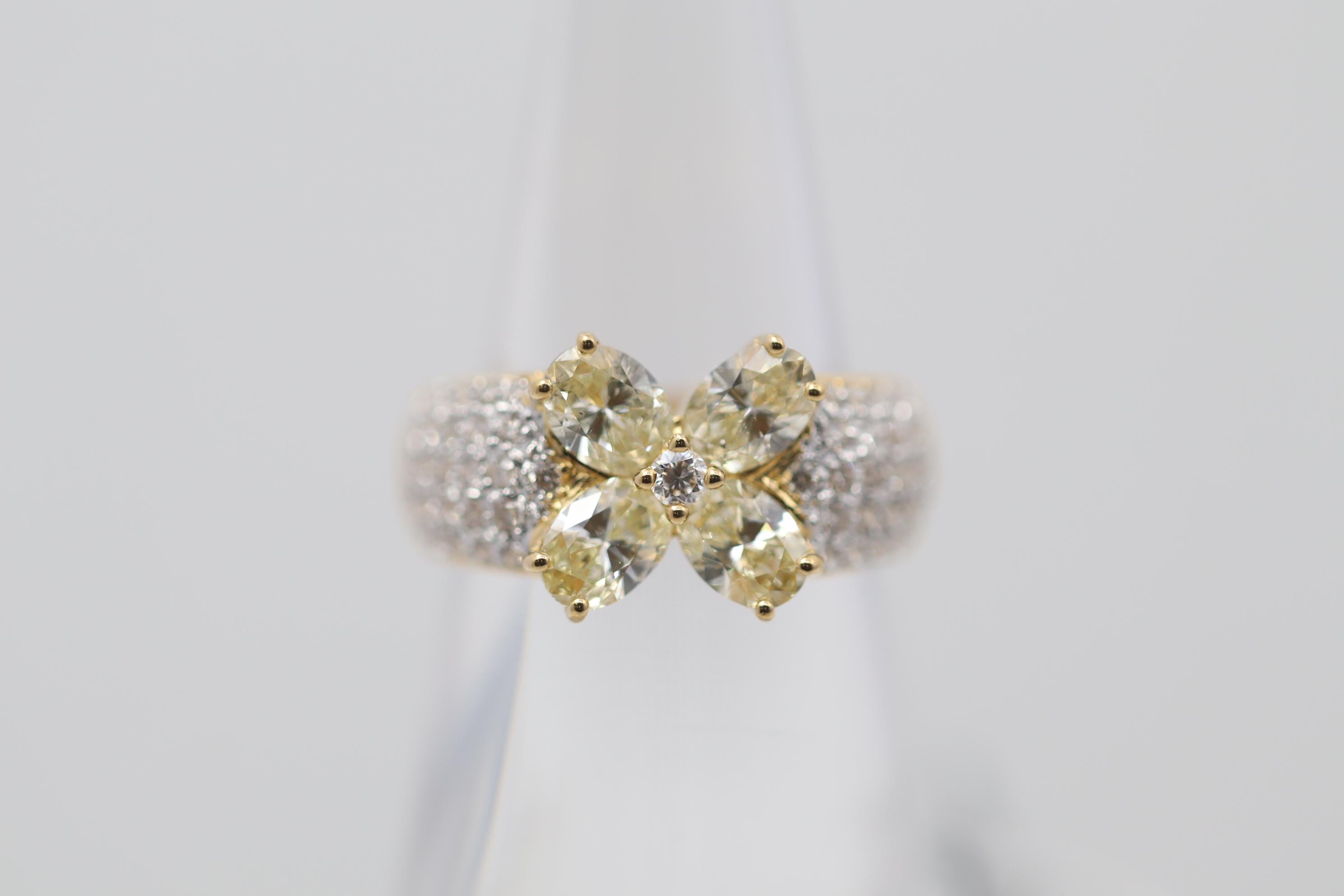 A cute yet substantial diamond ring featuring four large fancy yellow pear-shaped diamonds set together in the center of the ring to create a sweet flower. The four pear-shape diamonds weigh a total of 1.51 carats and are complemented by additional