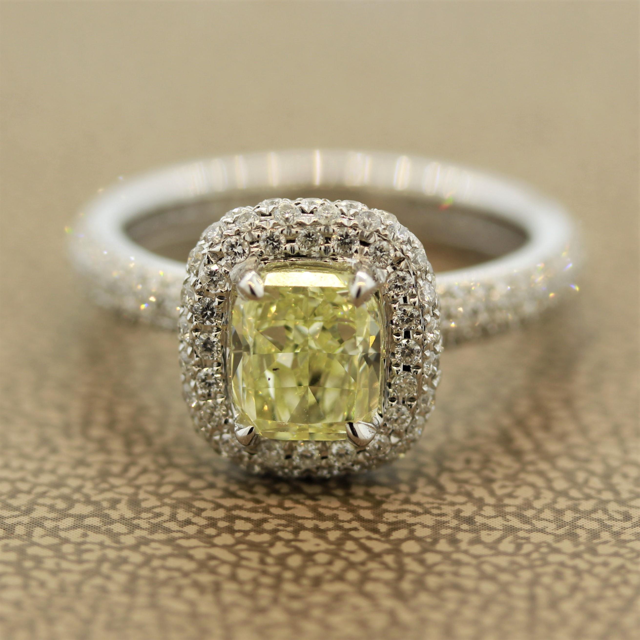 A stunning design, this engagement ring features a 1.32 carat cushion shaped fancy yellow diamond with VS clarity. It is accented by 0.95 carats of round brilliant cut diamonds set all around the basket of the ring as well are running down the shank