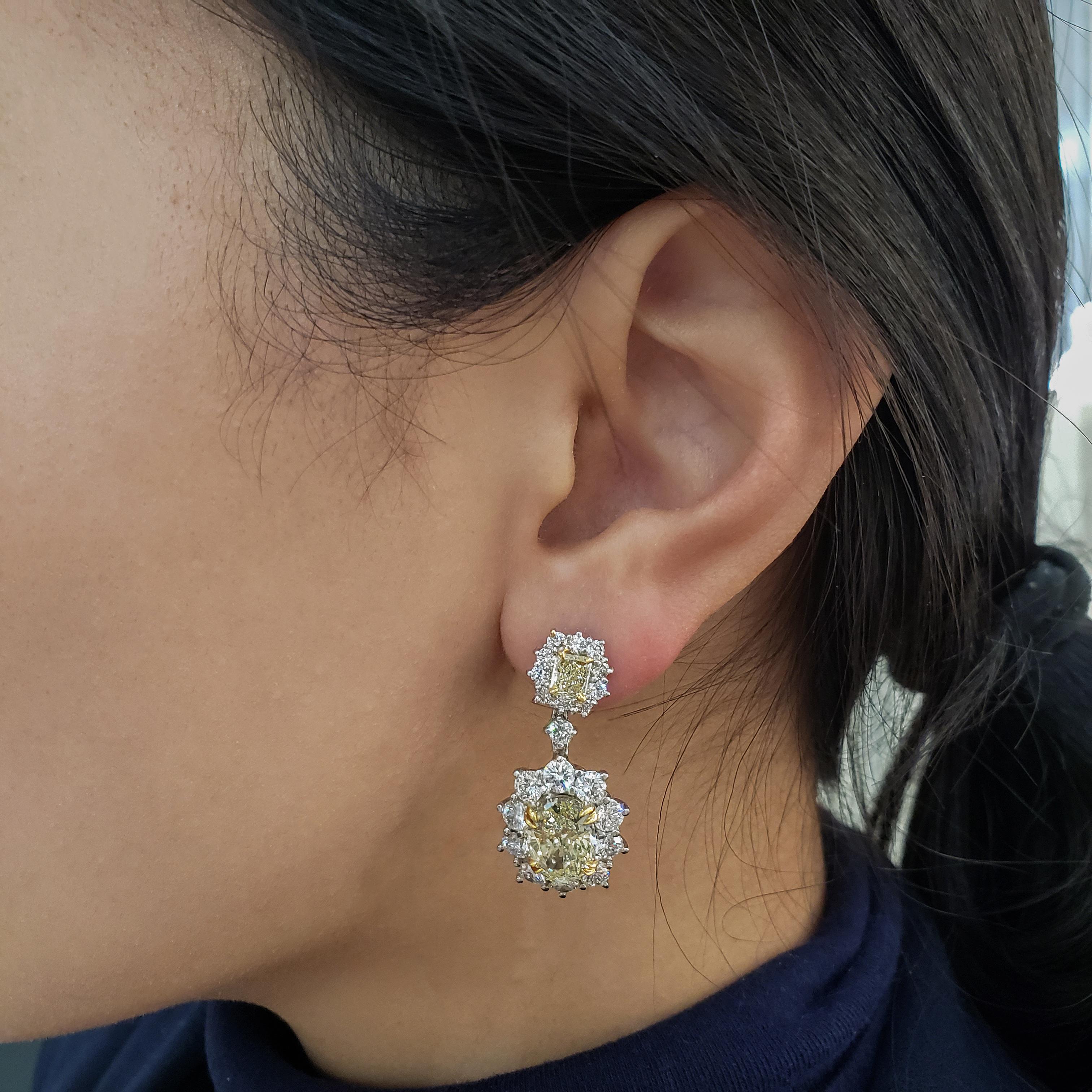Burst out in style with this gorgeous pair of 18k white gold earrings. Showcases 2 fancy yellow oval cut diamonds weighing 6.15 carats surrounded by sparkling round diamonds in a  creative floral motif design. Suspended on vibrant radiant cut yellow