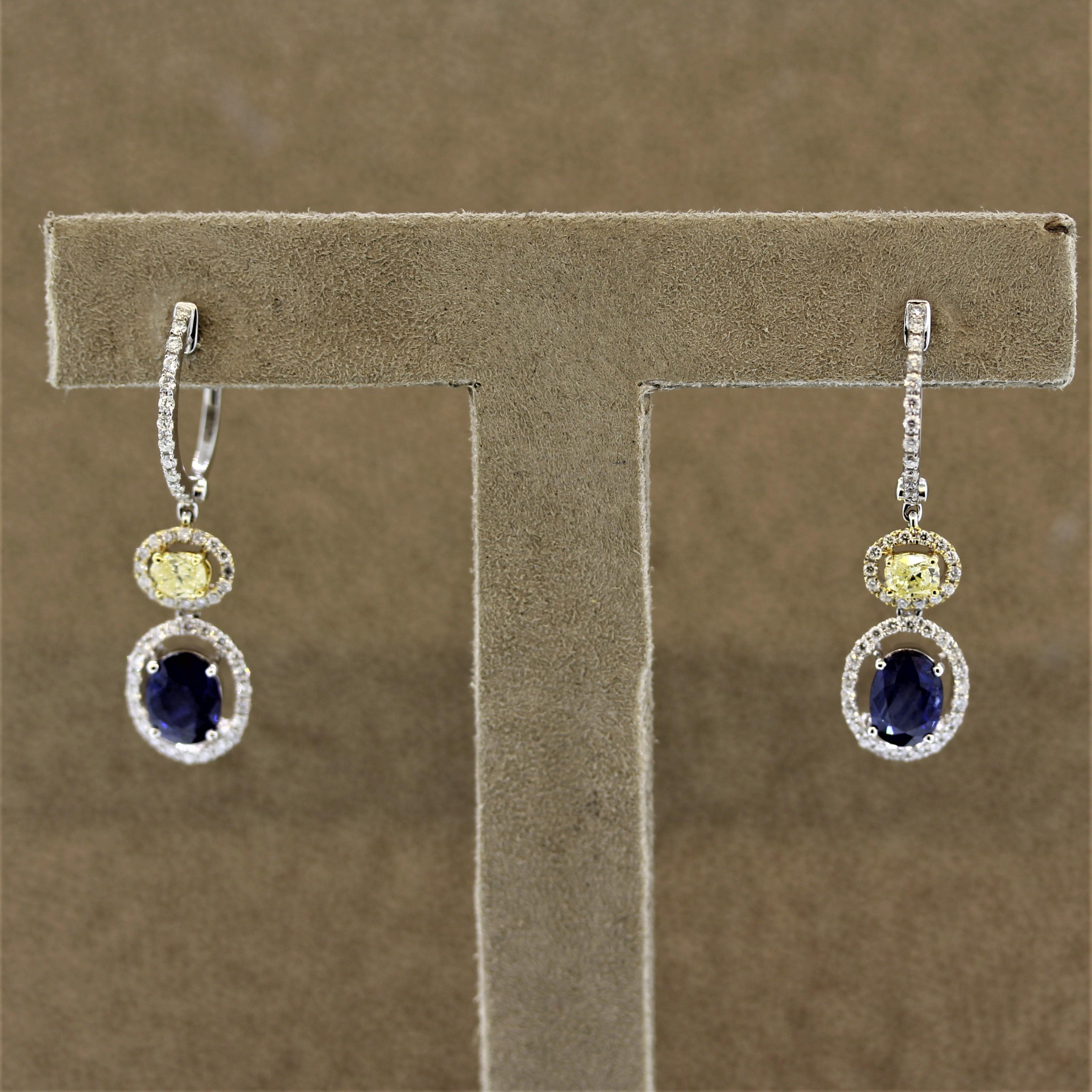 A lovely pair of drop earrings featuring fine blue sapphires and fancy colored yellow diamonds. The contrasting colors bring beauty to the piece. The blue sapphires are an oval shape and weigh a total of 2.48 carats, while the two fancy yellow