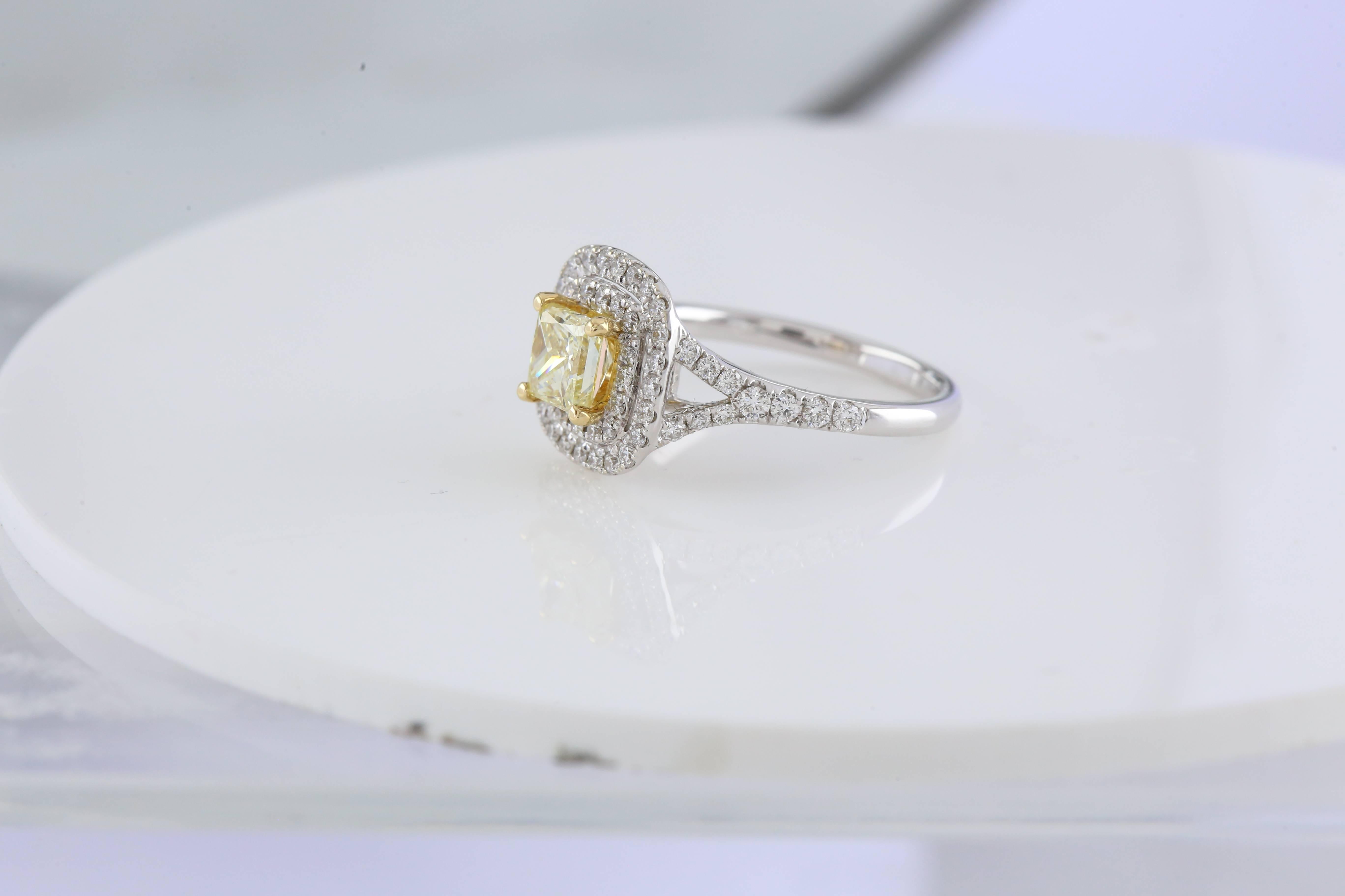 18ct White gold Princess Cut 0.96ct Fancy Yellow Diamond, HRD Certificated 1007501004, Clarity SI2, Polish VG,
Symmetry VG, Set in a double halo split shoulder diamond mount with 18ct yellow gold claws around centre diamond.