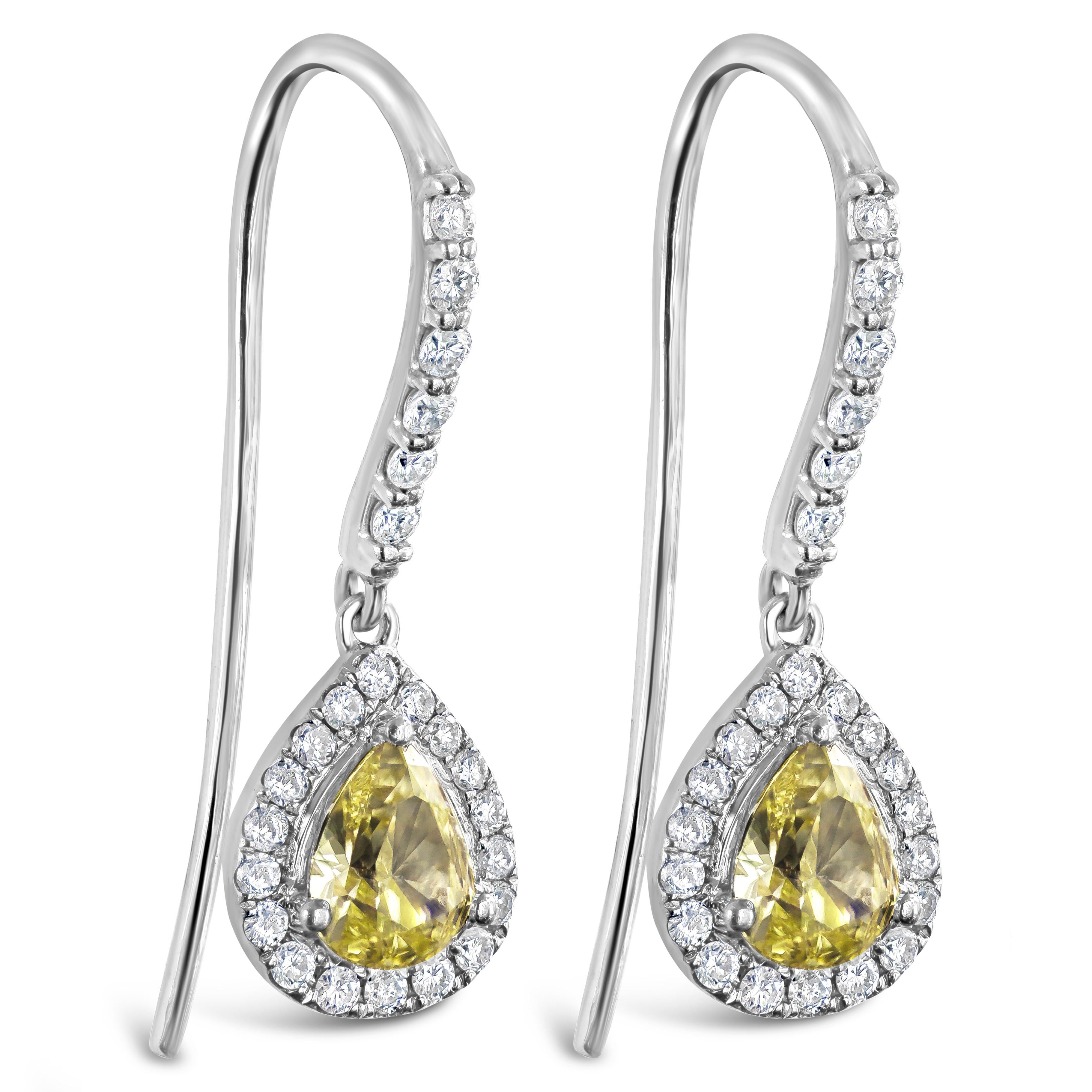 Color-rich pear-shaped yellow diamonds take the spotlight in this magnificent dangle earrings. Each yellow diamond is surrounded by a single row of sparkling round diamonds attached to an accented 18 karat white gold french hook. Yellow diamonds
