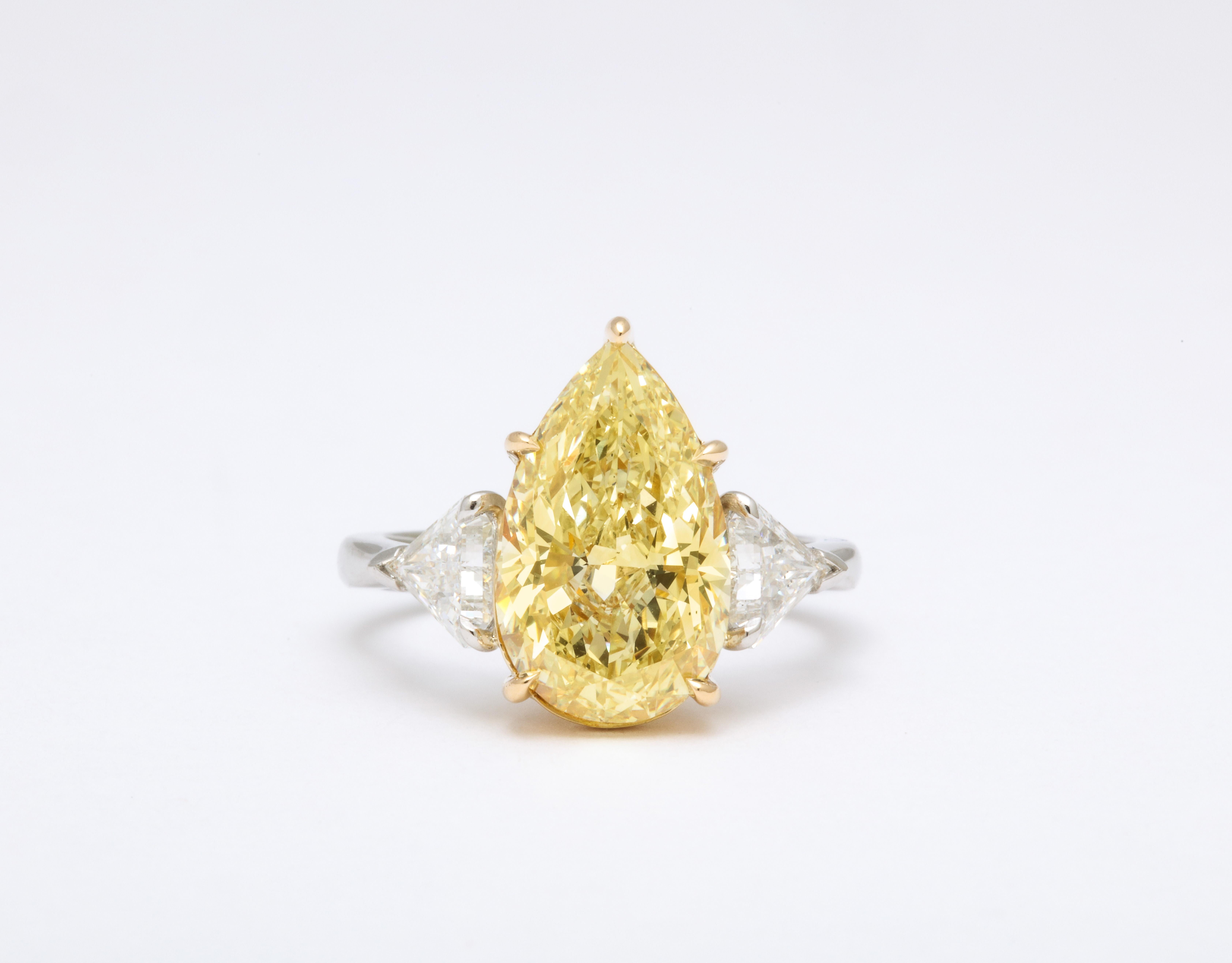 
A gorgeous stone and shape!

GIA Certified 4.57 carat Fancy Yellow, SI1 Pear shape center diamond. 

The center diamond measures 14.47mm long! 

.93 carats of white trillion cut side diamonds. 

Set in a custom made platinum and 18k yellow gold