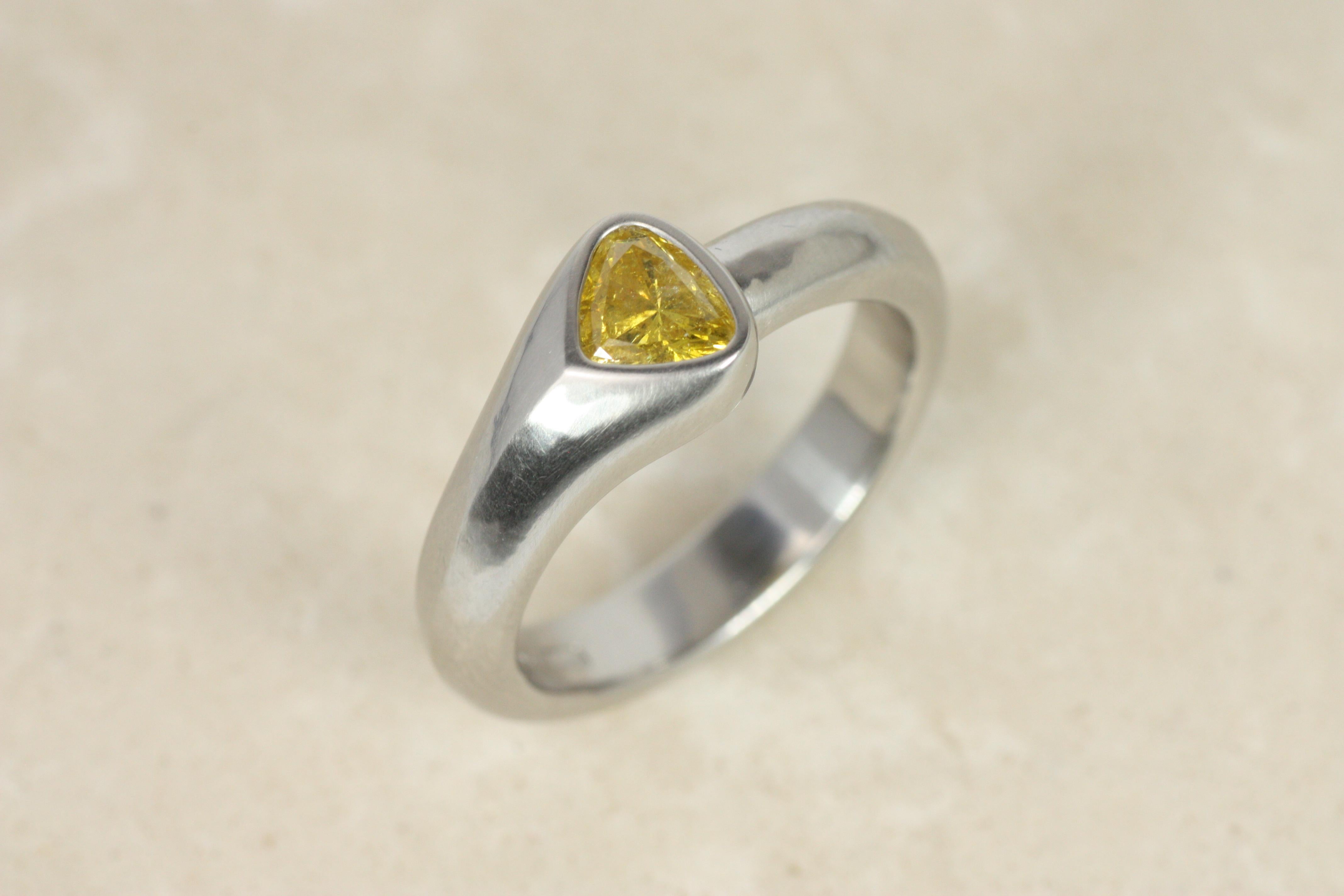 Este anillo solitario asimétrico, una versión moderna y orgánica de la elegancia, exhibe un raro diamante en forma de pera de color amarillo intenso fantasía. La llamativa banda de platino con filo de cuchillo sigue la curva natural del diamante,
