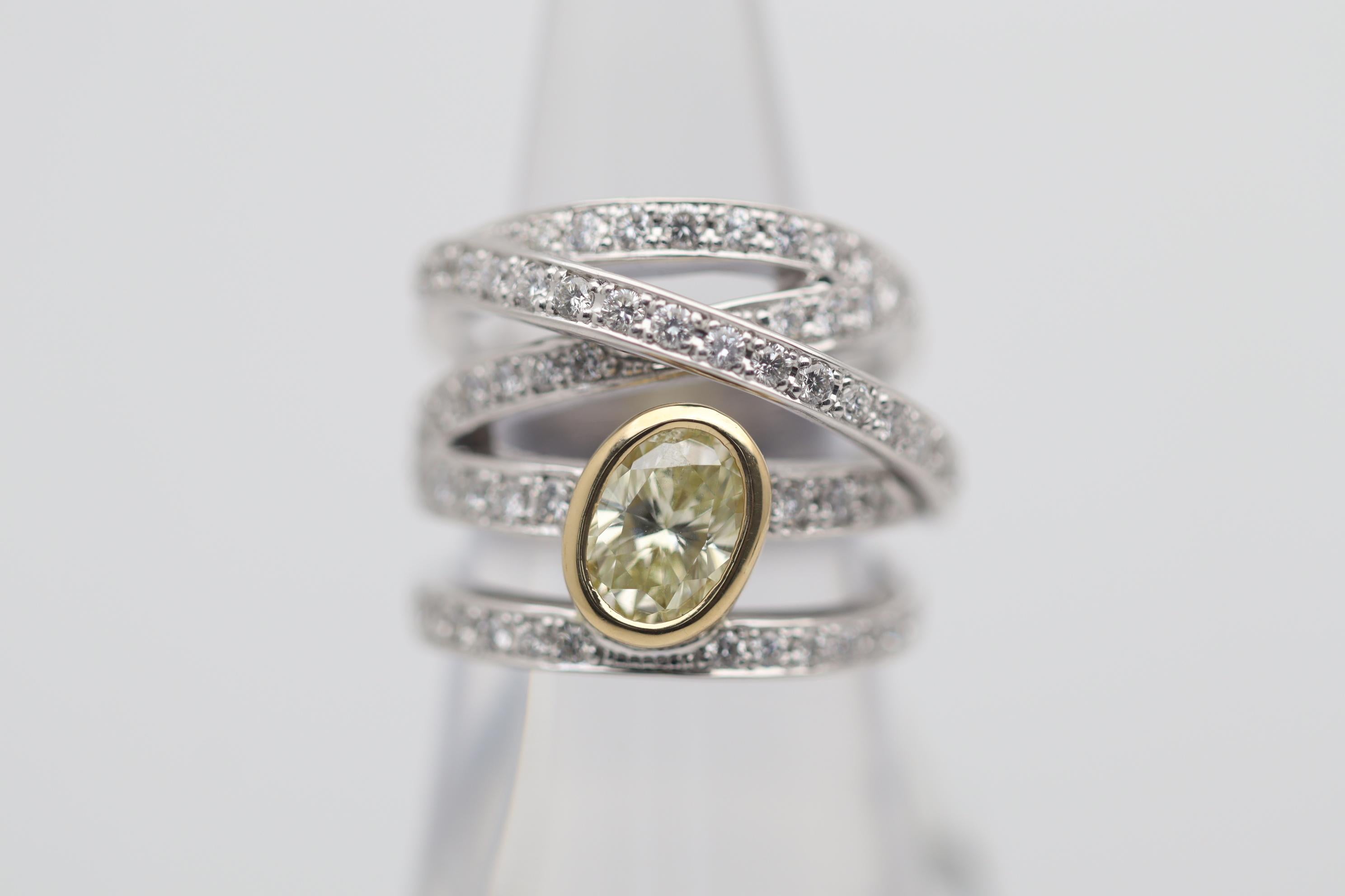 Un anello divertente ed elegante con un diamante giallo da 1,23 carati. Ha una bella forma ovale ed è incastonata in oro giallo 18 carati per aiutare a completare il colore naturale delle pietre. A ciò si aggiungono 1,18 carati di diamanti bianchi