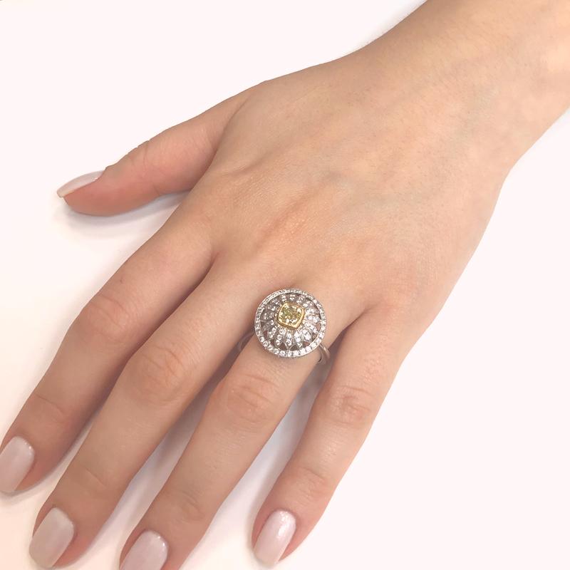 A unique fashion forward Art Deco inspired cocktail ring crowned with a french cut fancy yellow diamond 9.77 carat center piece stone with a yellow gold border.  It is surrounded with small round white natural diamonds laid out in a sunburst spread