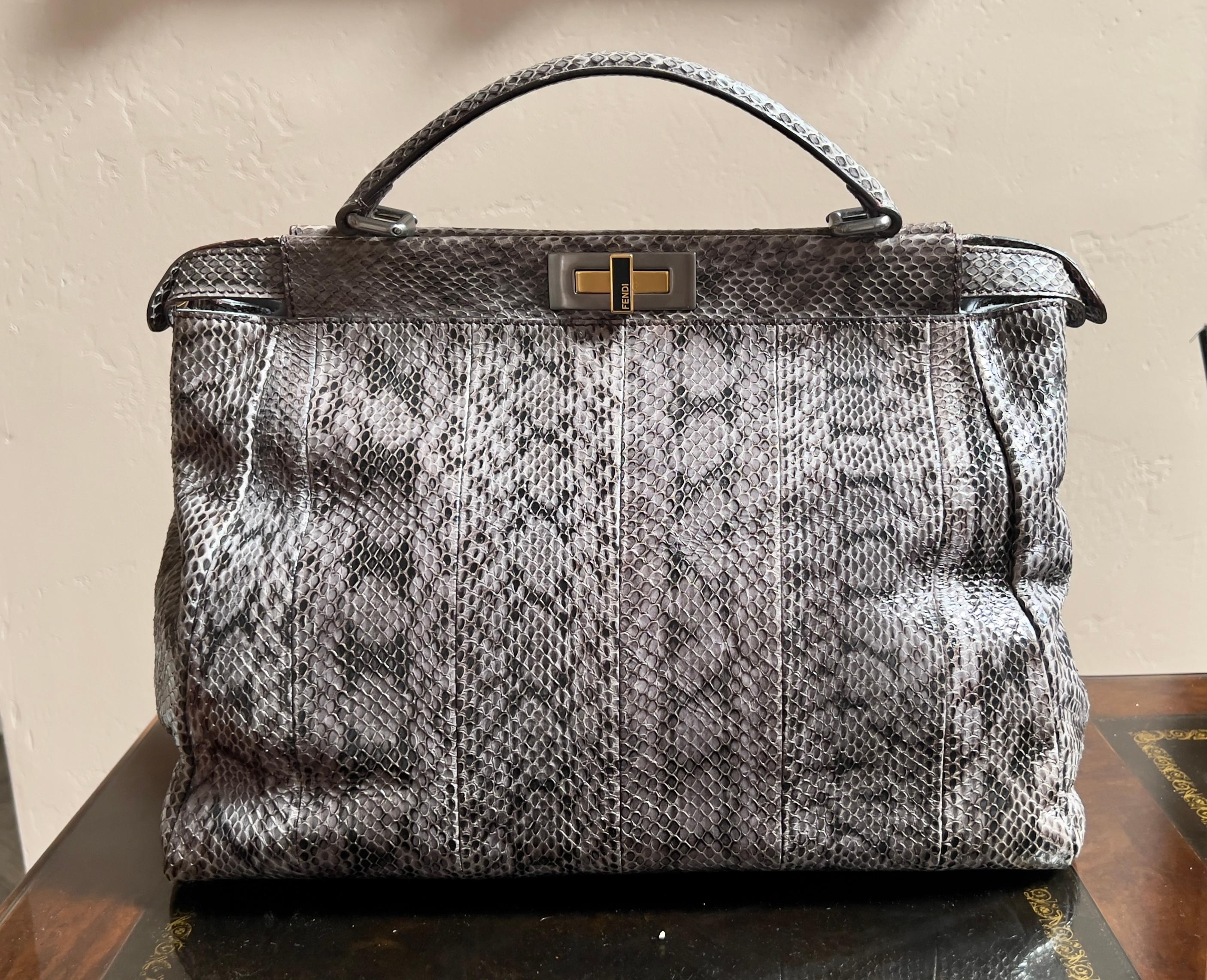 This beautiful Fendi skin peekaboo handbag tote is crafted of grey leather skin with silver, gold and black enamel accents. Black enameled turnlock hardware on both sides. Signature two large peekaboo compartments. Inner zipper compartment in one of