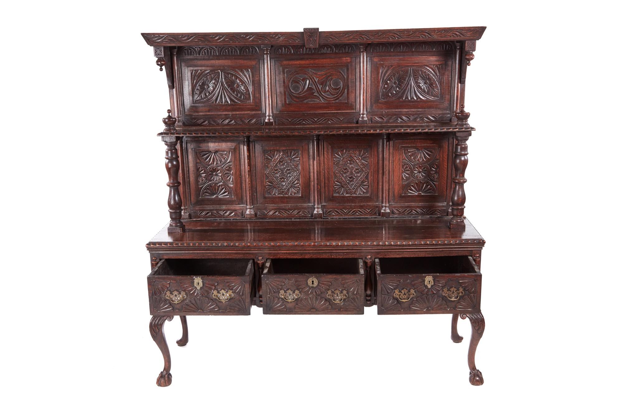 Fantastic antique carved oak dresser. The top section having seven beautifully designed hand carved panels, one shelf supported by two elegant turned columns. The base boasts three long carved drawers with original brass handles. It stands on lovely