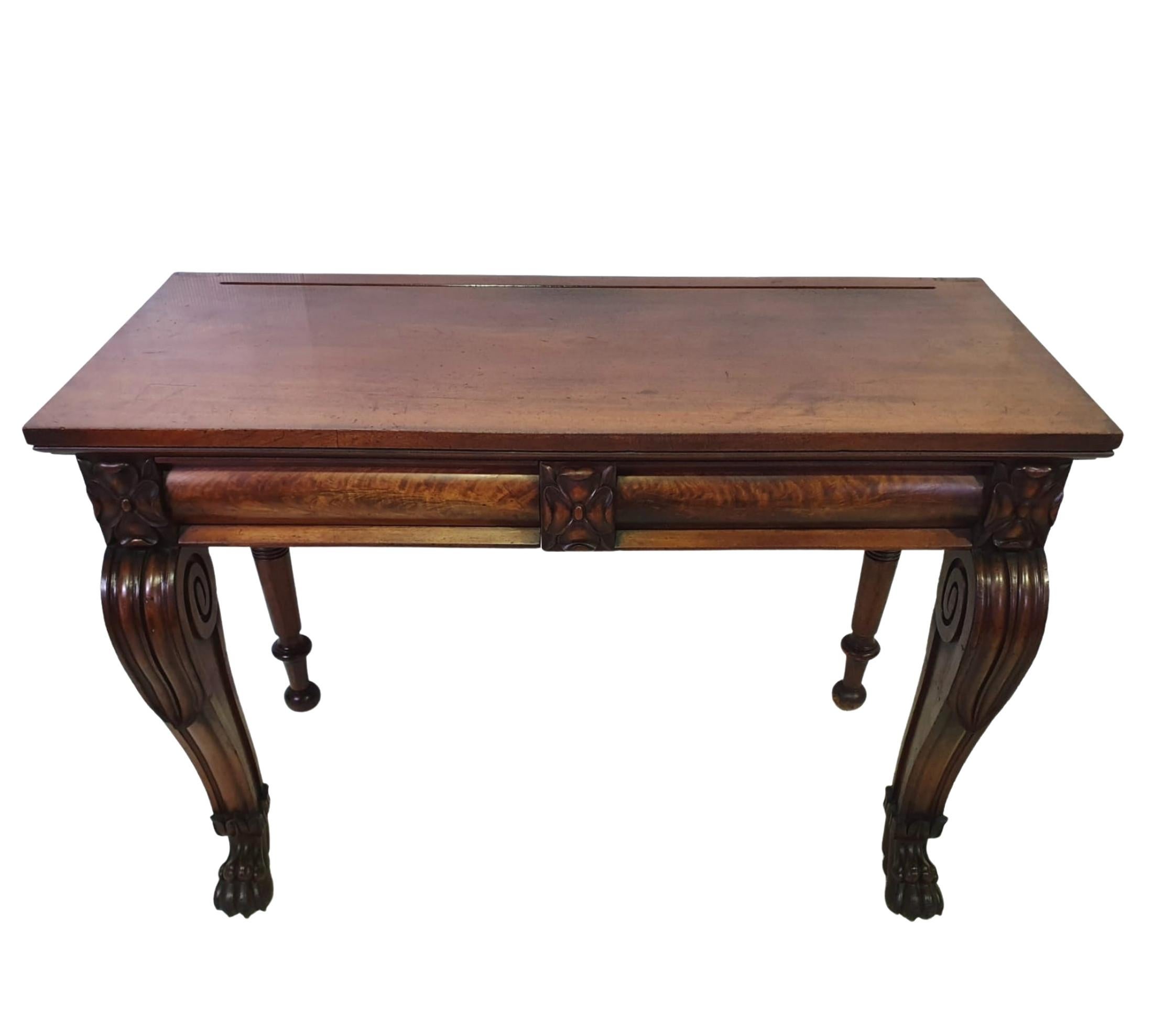 19th century Irish William IV mahogany console or side table. The moulded top raised over frieze with carved flower head motif supported on turned legs to the rear and beautifully carved scroll legs to the fore terminating on lion paw foot.