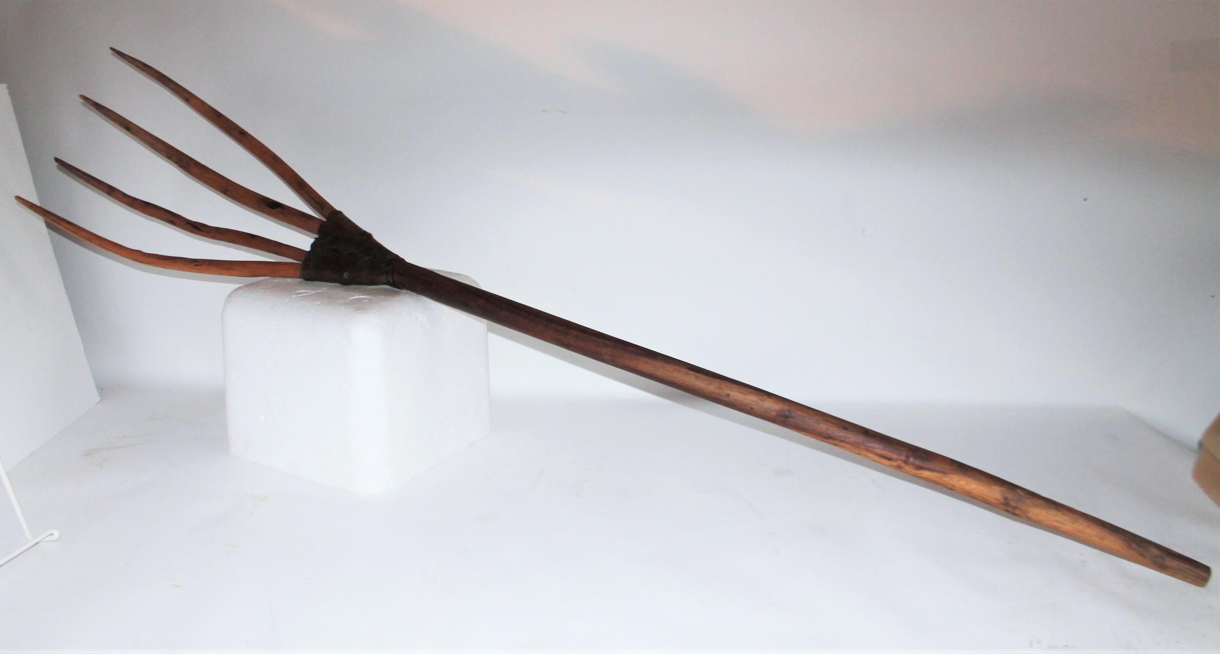 This early handmade fork has a wonderful worn patina and is reinforced with rawhide, leather guard at the bottom of the prongs. The wood is a worn hickory wood carved out from one piece of wood. Great for hanging on a wall or next to the hearth of a