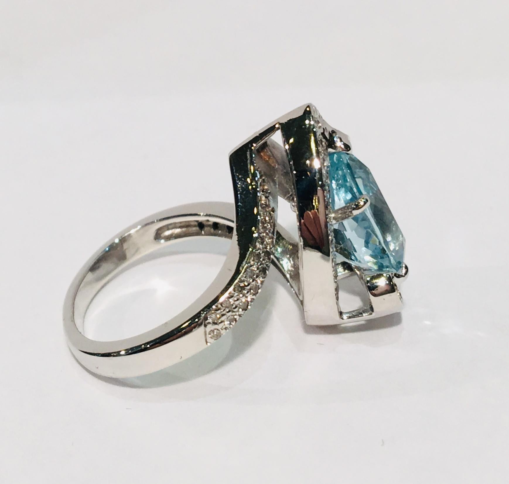 A large, sparkling pear cut aquamarine is prong set at an angle in 18 karat white gold and embellished with a two-tier halo of pave set diamonds in this contemporary estate ring.  Pave diamonds also adorn the shank, which connects to the point of