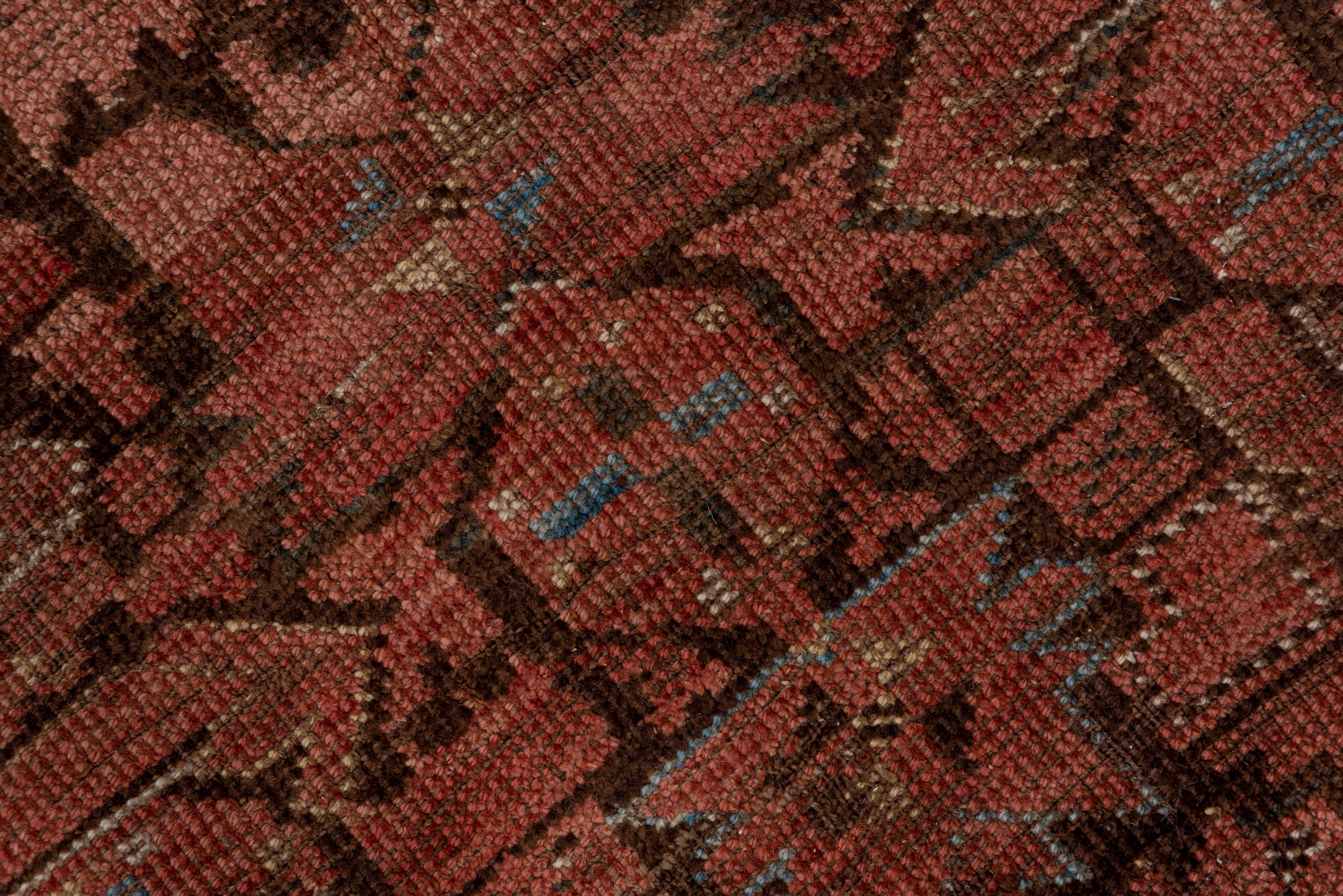 The dark red-brown field on this gallery carpet is closely covered by a Turkmen tribal geometric version of the classic Persian Herati design, overlaid by small octagonal motives. The borders show octagons and eight-fold divided squares. The red is