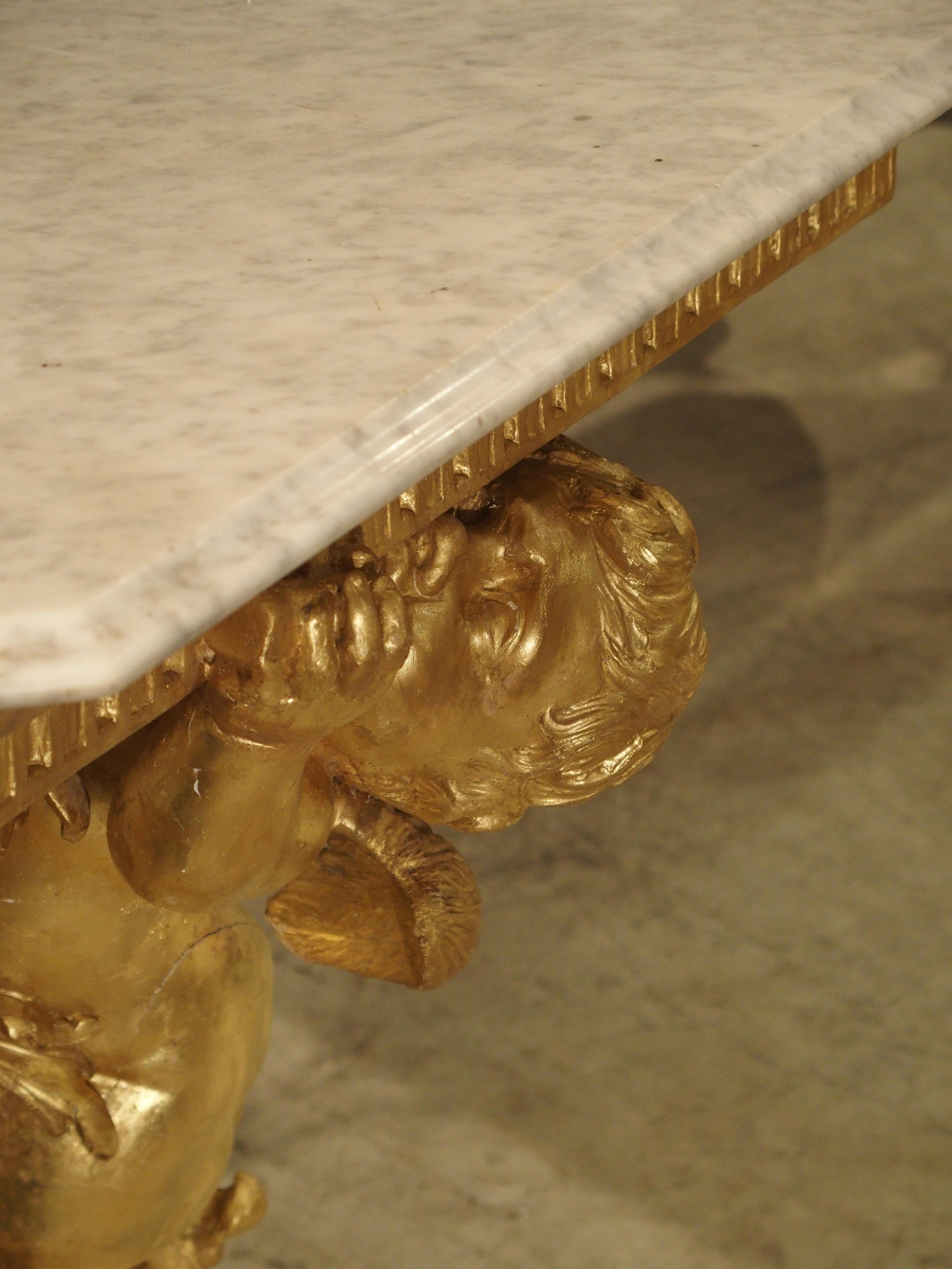 This exceptional antique giltwood console has been carved showing movement in its subject, the large cherub. The determined cherub is using his entire body to place an item in his left hand on top of the console. His right shoulder is pressing