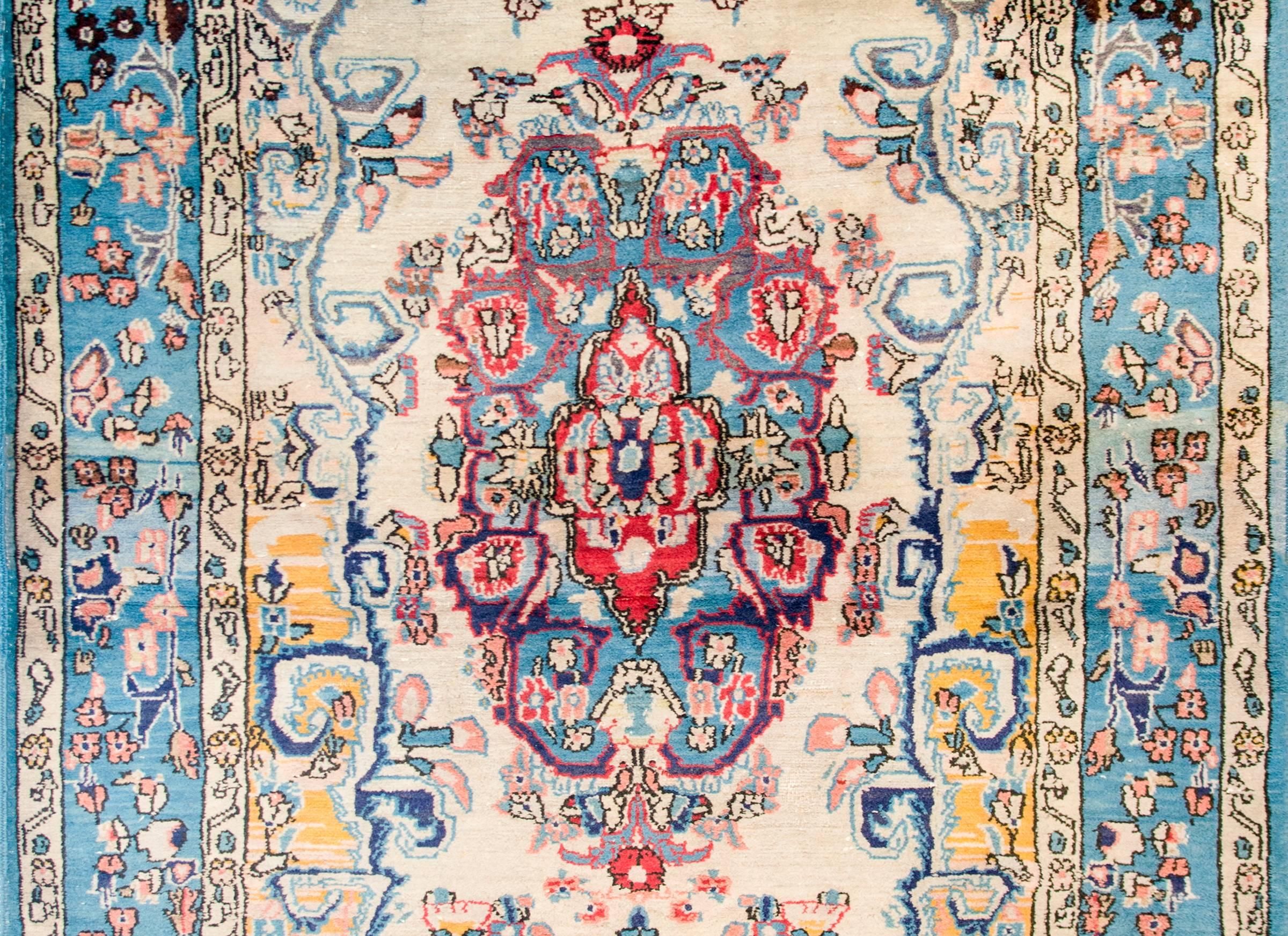 A fantastic early 20th century Persian Tabriz rug of with a large central floral medallions woven in crimson, pink, indigo, and gold wool amidst a field of scrolling leafy vines on a cream colored background. The border blends in amazing, with a