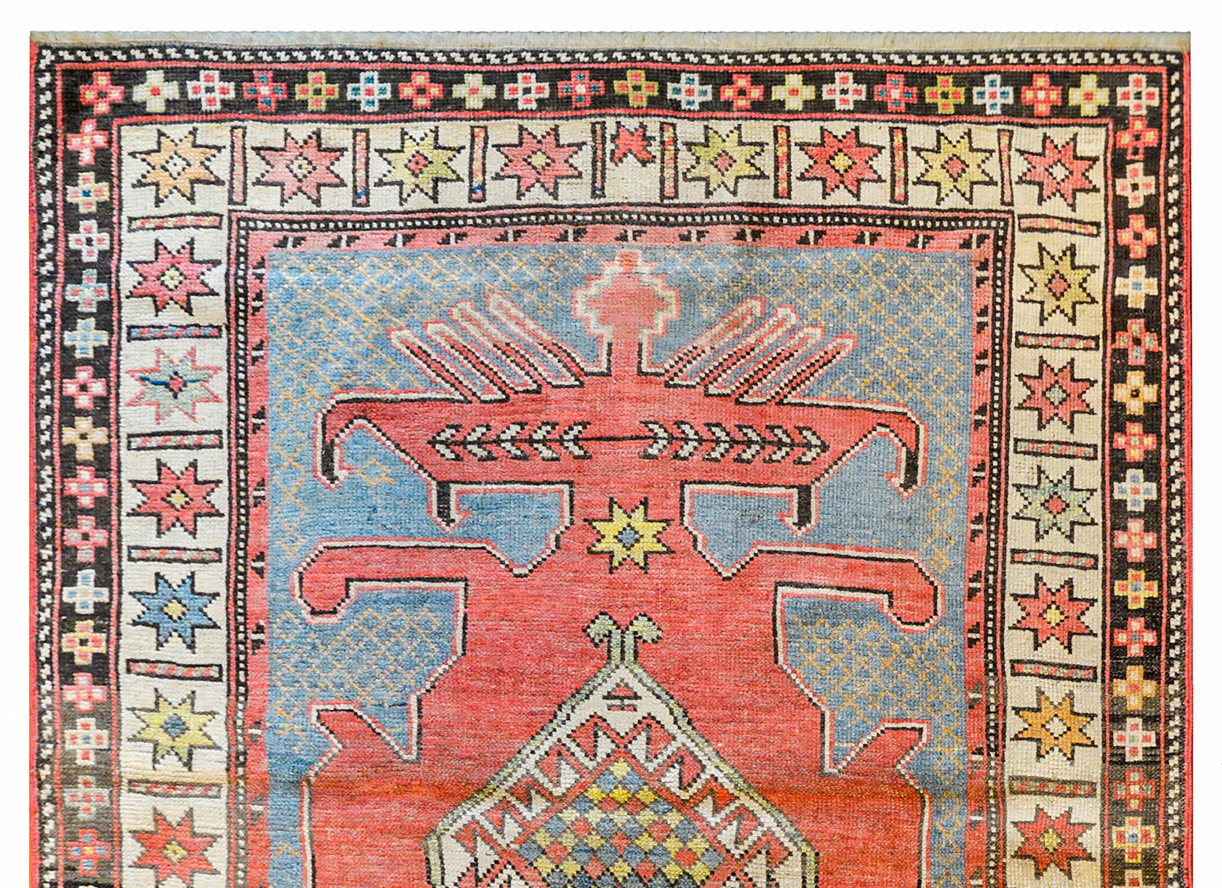 A fantastic early 20th century Azerbaijani Kazak rug with a large medallion with a white diamond in the center surrounded a by a elaborate coral colored stylized floral and scrolling vine surround on a pale indigo ground with a yellow trellis