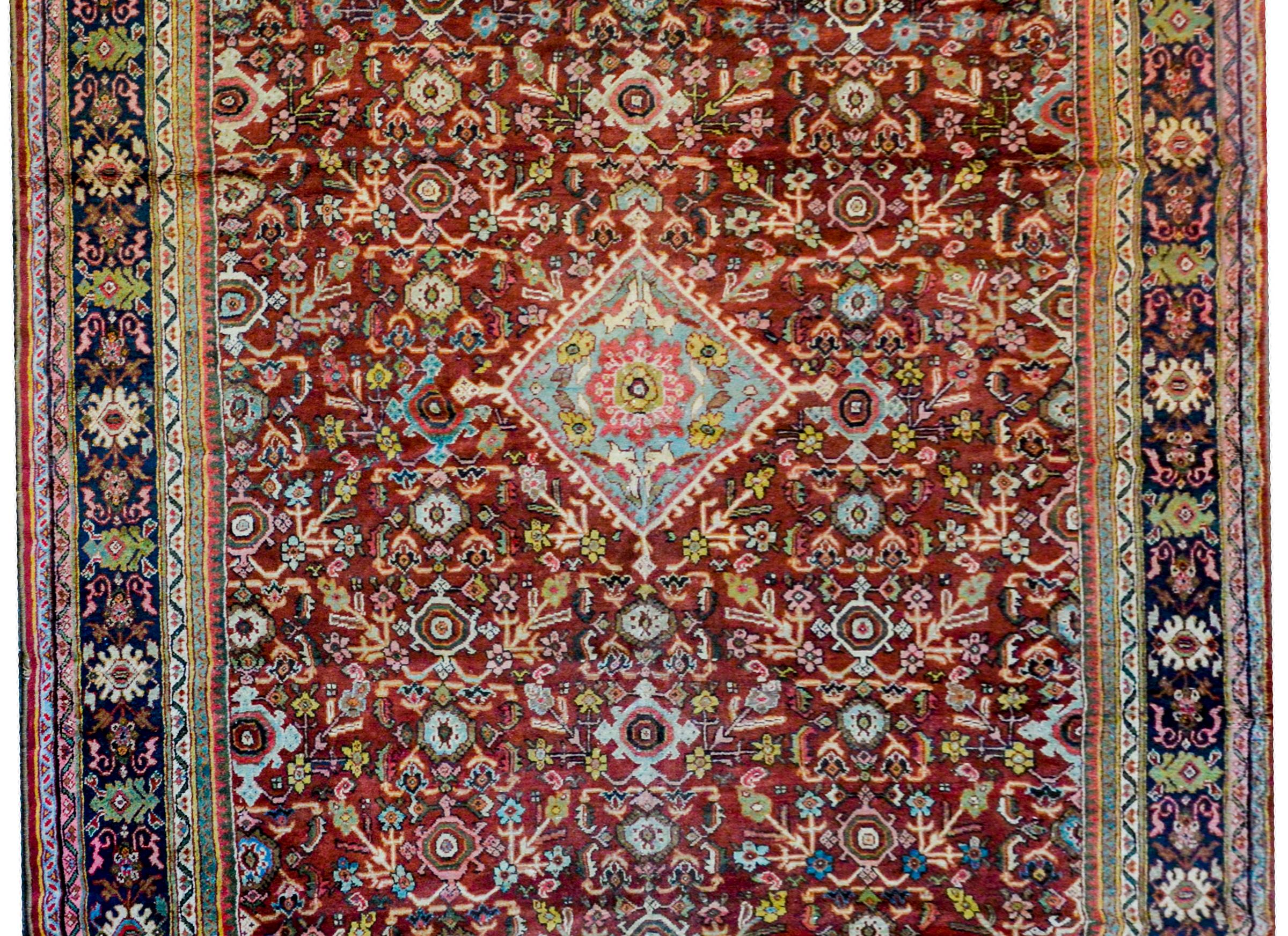 A fantastic early 20th century Mahal rug with an all-over lattice pattern of myriad flowers and leaves woven in white, light indigo, green, and gold vegetable dyed wool on a dark crimson colored background.  The border is wonderful with a wide
