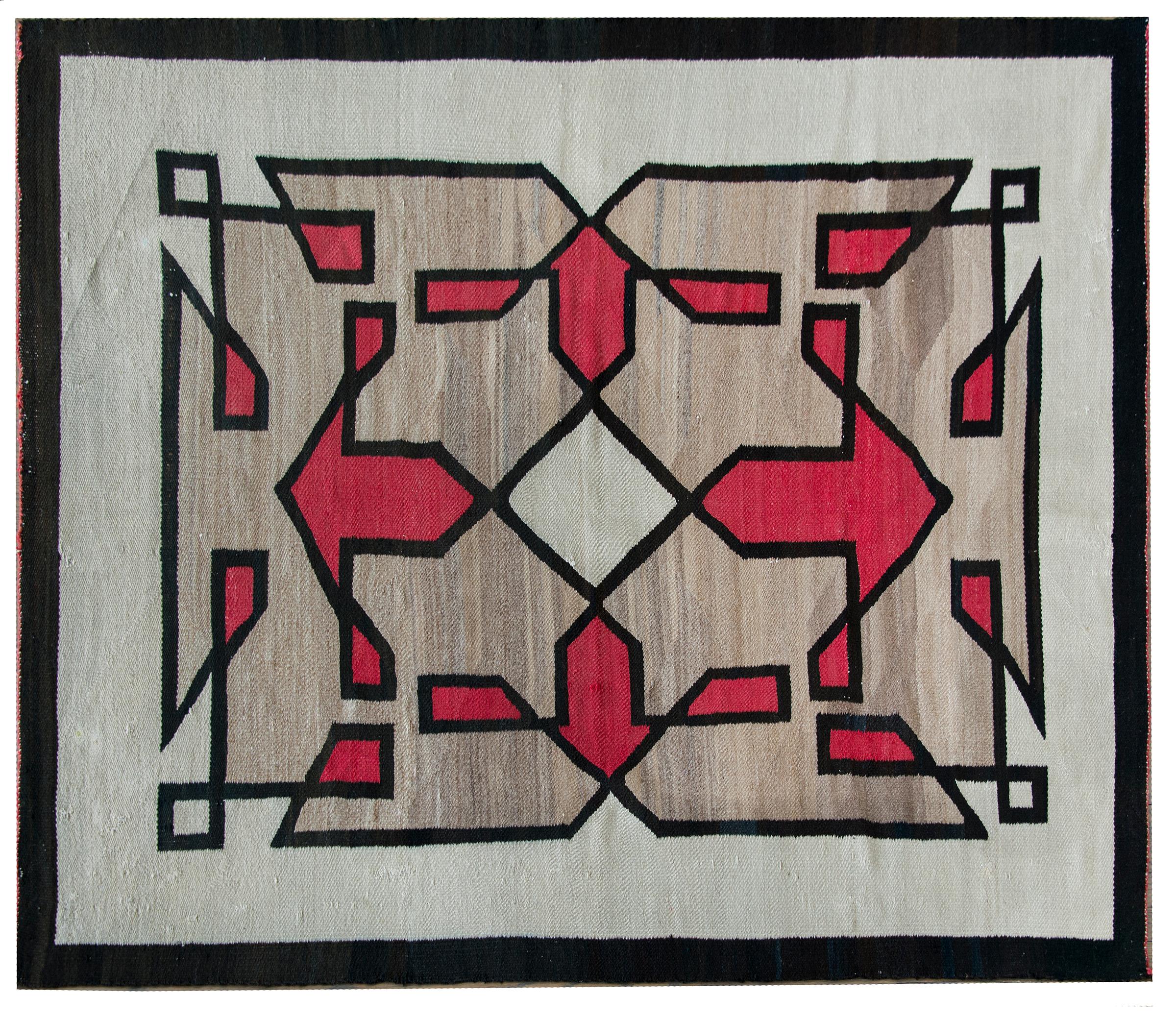 A fantastic early 20th century Navajo rug with four large red arrows pointing outward from a central white diamond, and living amidst a field of other geometric shapes on an abrash natural gray wool background, and all surrounded by a thin back