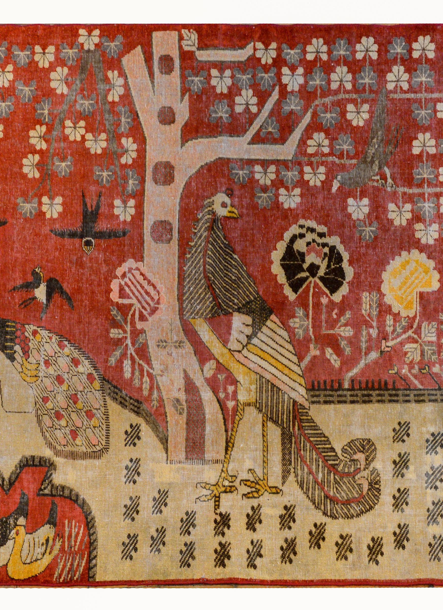 A fantastic early 20th century Central Asian pictorial Khotan rug depicting myriad birds including peacocks, cranes, ducks, magpies, and doves, all nestled in a lush floral landscape containing peonies and cherry blossoms.