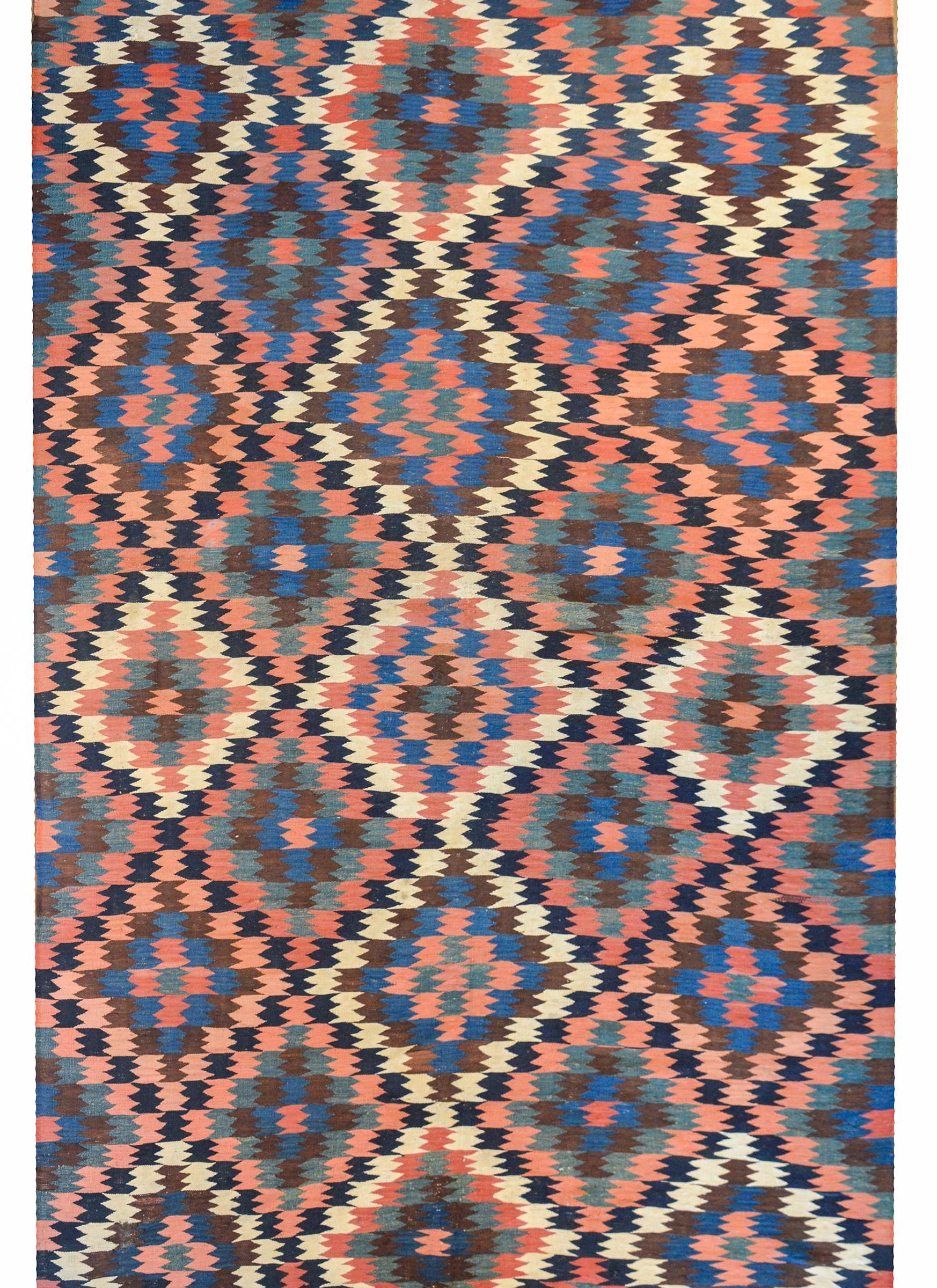 A fantastic early 20th century Persian Shahsevan kilim rug with an all-over diamond pattern woven in light and dark indigo, coral, cream, and green vegetable dyed wool. There is no border.