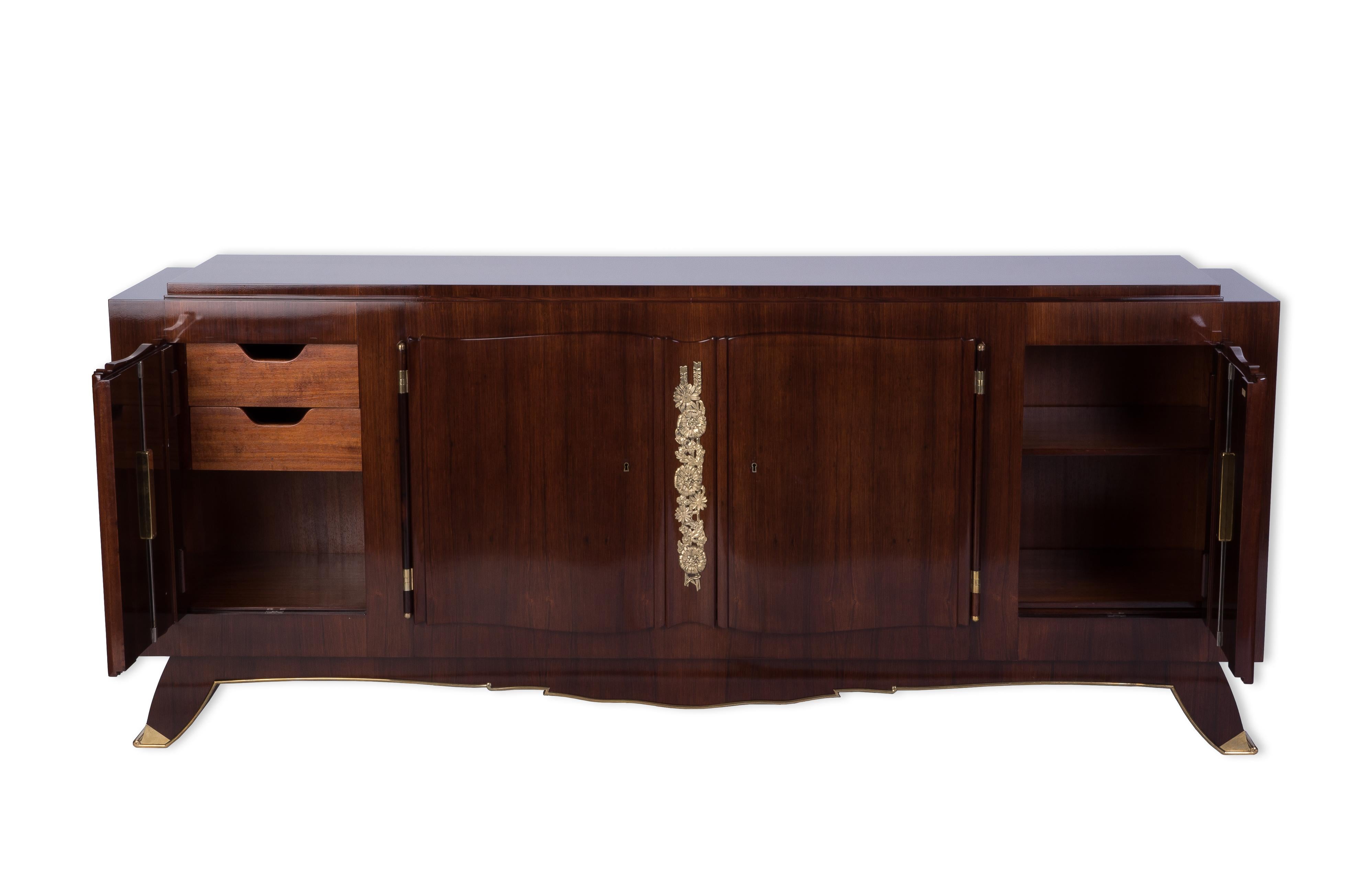 This fantastic Art Deco sideboard or credenza was designed and executed by Jules Leleu in a solid mahogany frame veneered in rosewood with a French polish finish and signed with aplaquette inlaid on door. It features four doors with floral motif