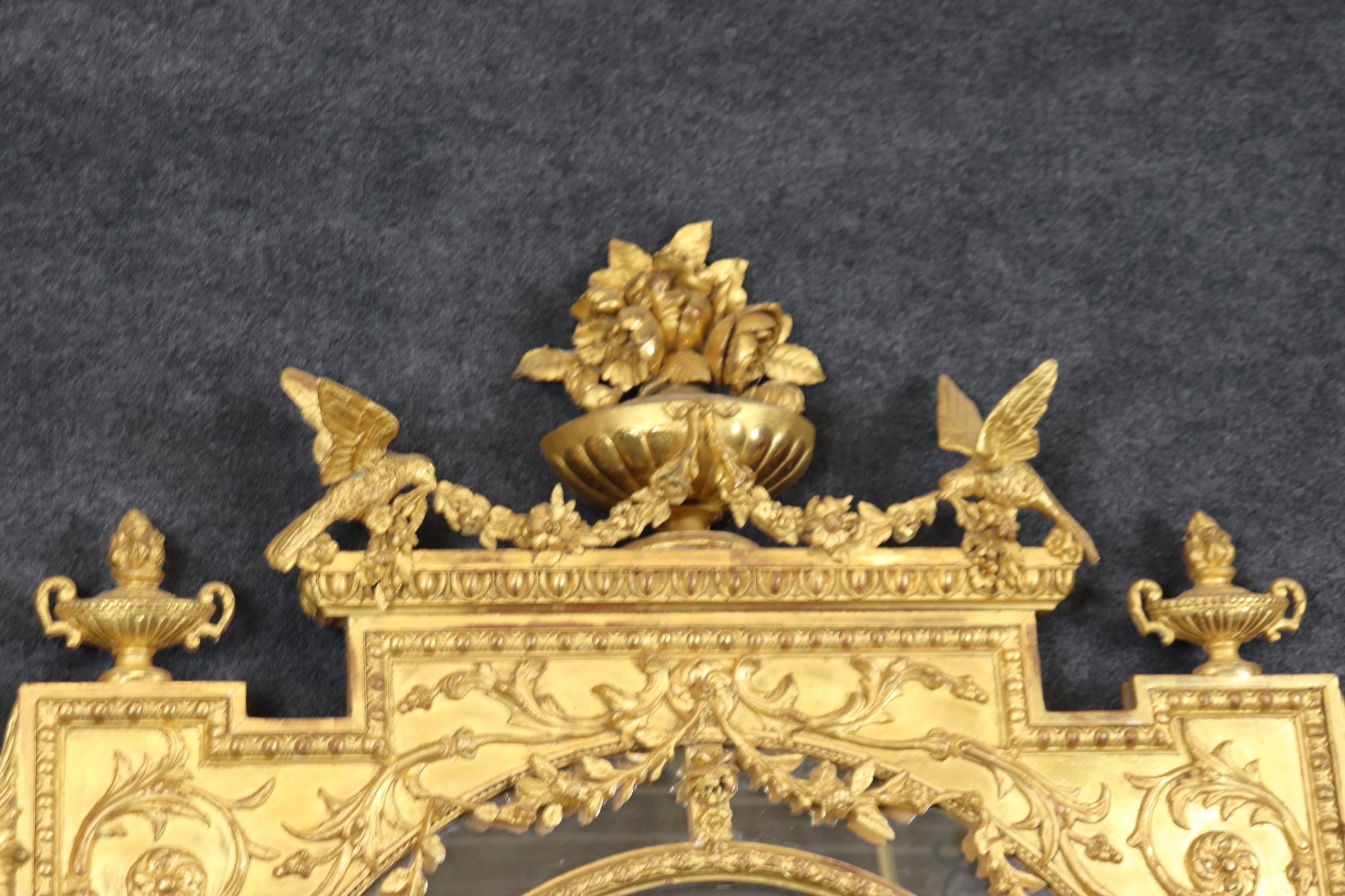 This spectacular gilded mirror dates to the 1880s era and is French. The mirror features full body carved birds with floral bouquets and full-figured maidens on each side. The mirror is in gorgeous water-gilded and water-gilded gold leaf and is in