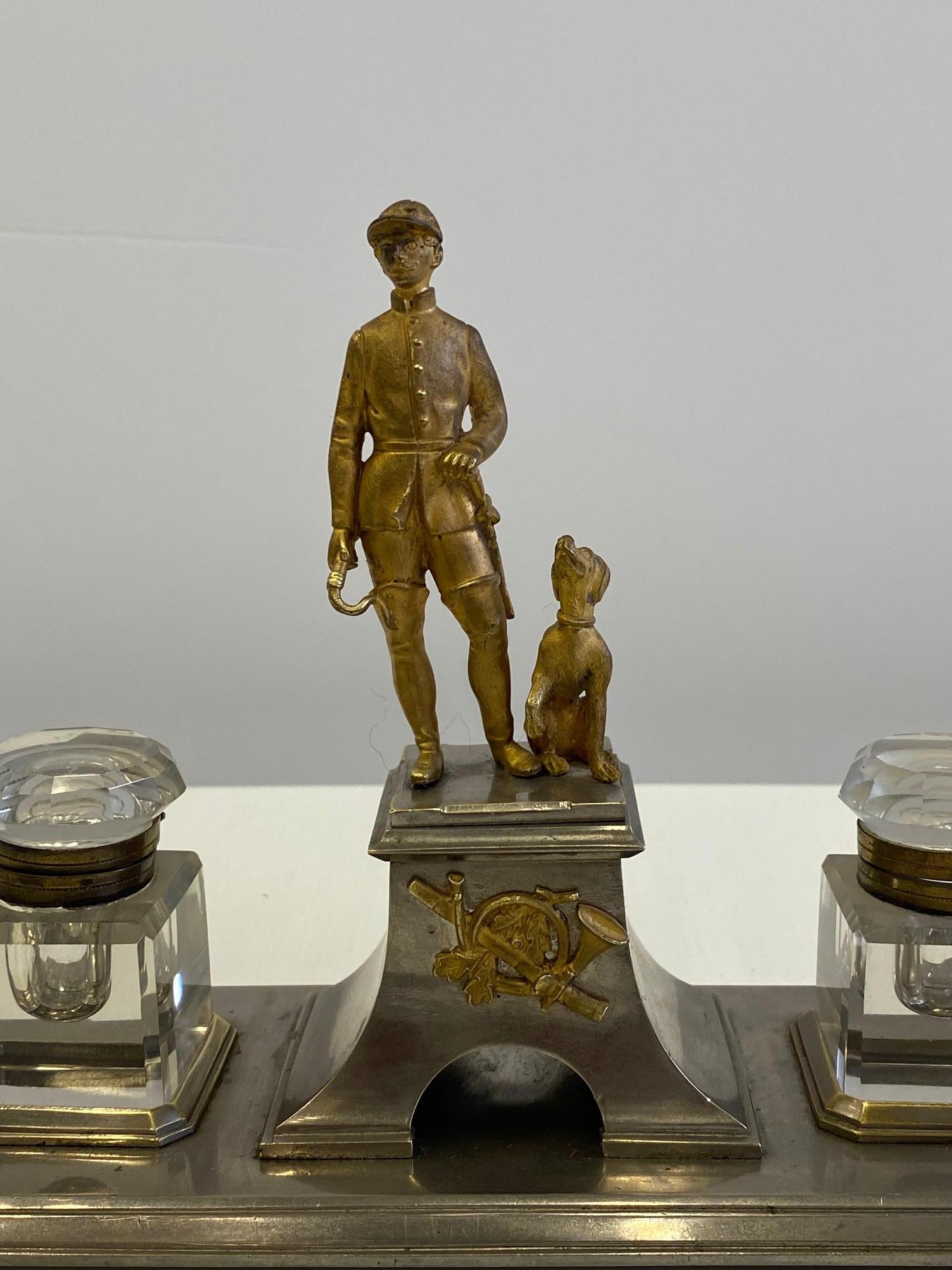 Marvelously detailed French antique desk accessory inkwell made of gilt bronze and nickel plate having sculptural horseman in period outfit accompanied by loyal hound dog at his side. There are two beautiful cut glass inkwells.
  