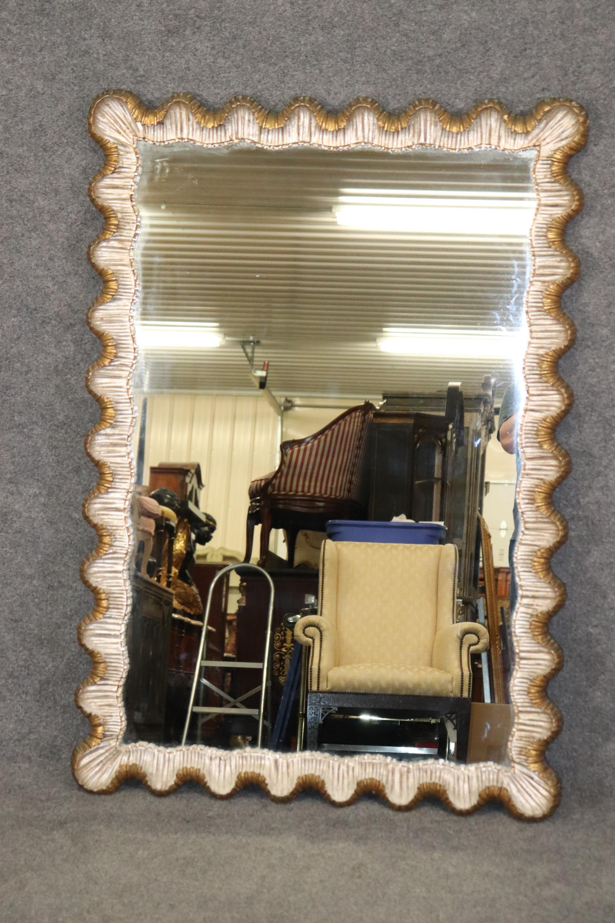This is a beautiful Grotto style mirror of the Rococo manner. The mirror is hand-carved scalloped wood and features gorgeous gold and silver leaf details. The mirror is in good condition and measures 52.25 tall x 36.25 x 2.5 deep and dates to teh